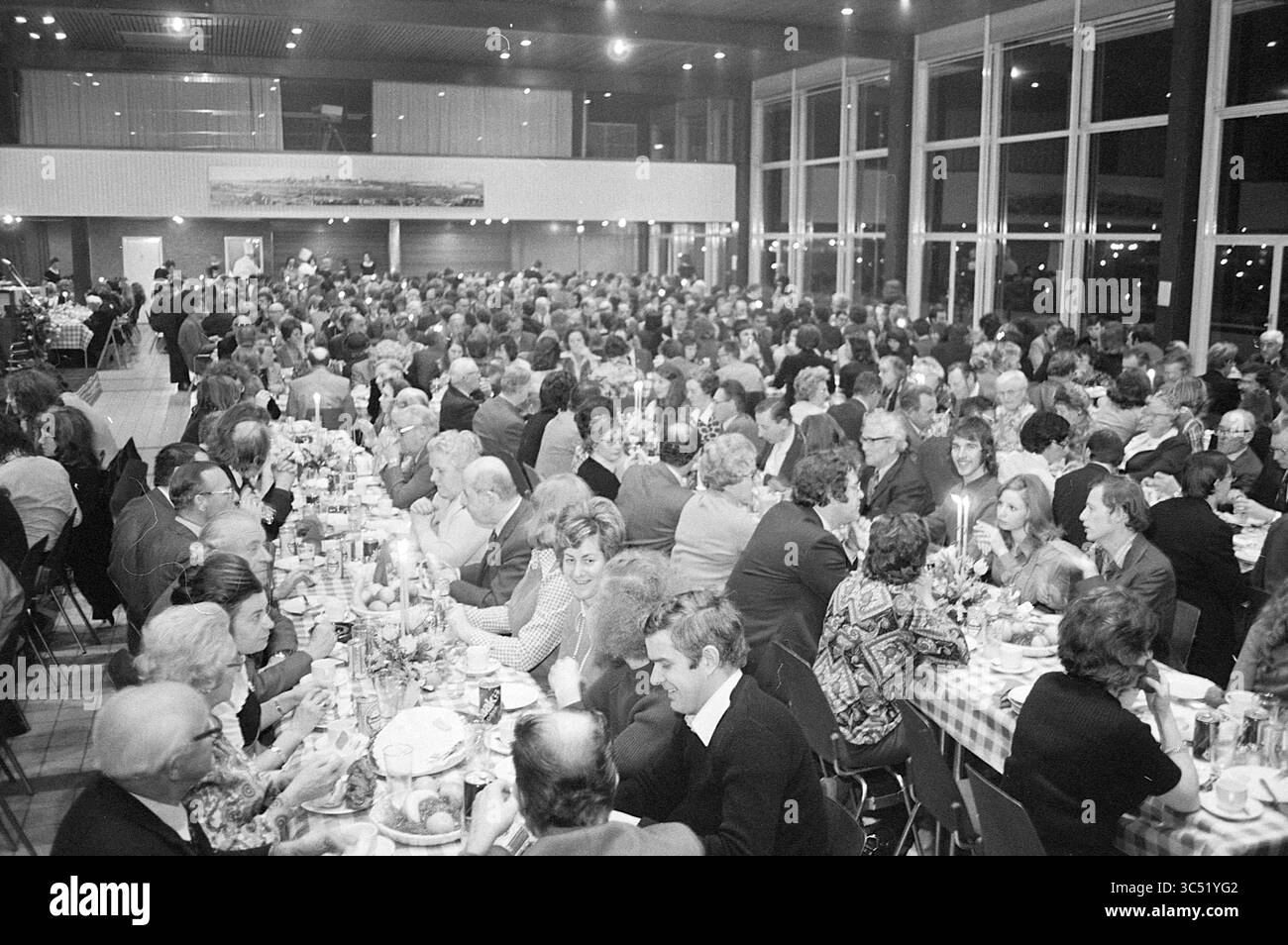 Chowder Meal, Hochofen-Schachturnier, 02-02-1974 Whizgle News, Dutch Desk, Niederlande, 1950-2000 Eine große Versammlung von Menschen, die an langen Tischen mit Essen und Getränken saßen, in Gesprächen und in festlicher Atmosphäre in einem geräumigen Saal mit großen Fenstern und dezenter Beleuchtung saßen. Stockfoto