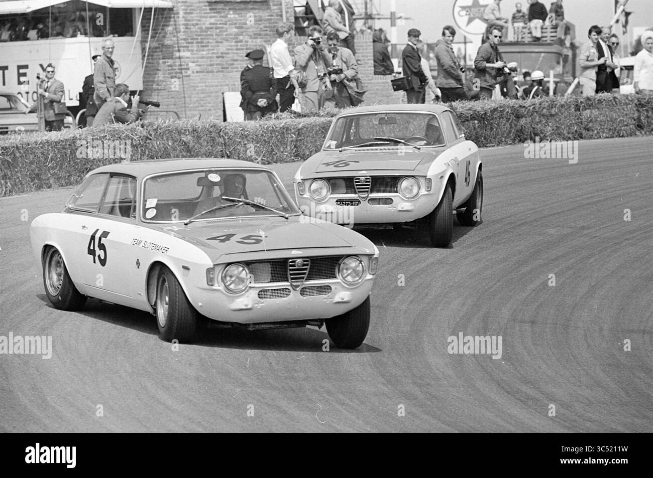 Autorennen mit Tourenwagen auf der Zandvoort Strecke, Zandvoort, 24-06-1966 Whizgle News, Dutch Desk, Niederlande, 1950-2000 zwei klassische Rennwagen bewegen sich während eines Oldtimer-Motorsport-Events auf einer geschwungenen Strecke und zeigen ihr schlankes Design und ihren Wettkampfgeist, während ein Publikum begeistert von der Seitenlinie zusieht. Stockfoto