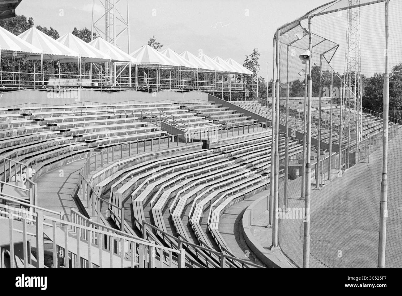 Construction HHD, 06-07-1992 Whizgle News, Dutch Desk, Niederlande, 1950-2000 ein leeres Stadion verfügt über mehrstufige Sitzplätze in halbrunder Anordnung, flankiert von Zelten und einem hohen Zaun, was ein Gefühl der Vorfreude auf bevorstehende Veranstaltungen vermittelt. Stockfoto