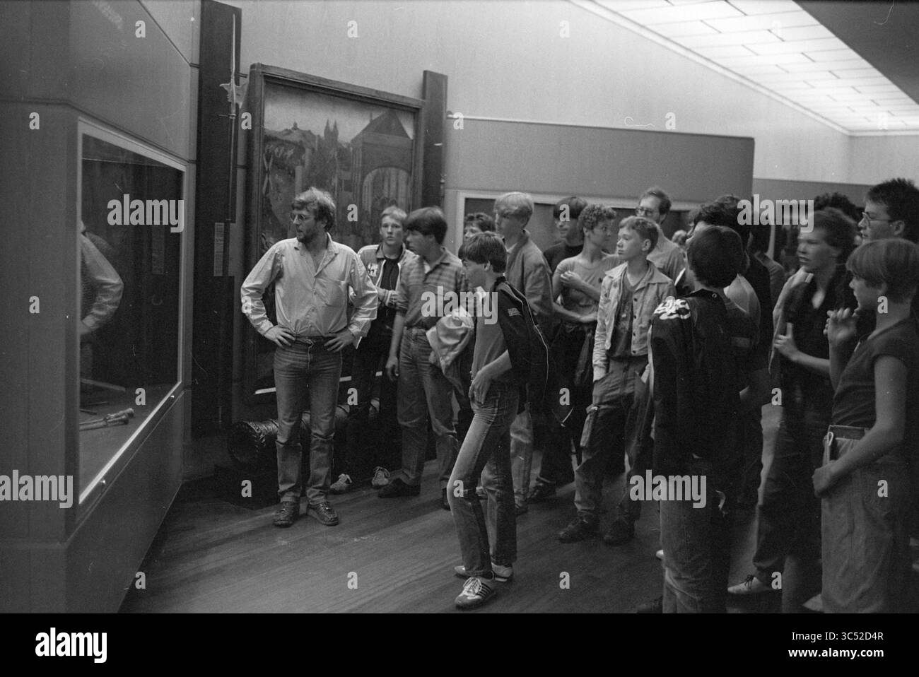 Rijksmuseum, Amsterdam, Survival Tour, Amsterdam, Niederlande, 16-07-1983 Whizgle News, Dutch Desk, Niederlande, 1950-2000 Eine Gruppe von Studenten hört aufmerksam einem Reiseleiter zu, der von einer Ausstellung in einem Museum umgeben ist, umgeben von verschiedenen Kunstwerken. Stockfoto