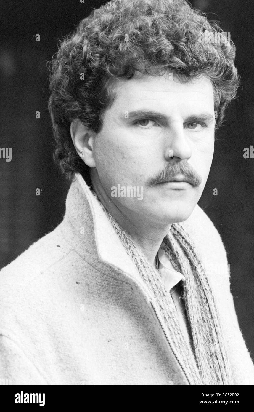 Porträts Robert Long, Robert Long, 04-03-1977','08-04-1980','03-10-1981 Whizgle News, Dutch Desk, Niederlande, 1950-2000 Ein Mann mit ausgeprägtem Lockenhaar und Schnurrbart blickt direkt auf den Betrachter, trägt einen hohen Kragen und einen strukturierten Schal. Sein Ausdruck ist ernst und strahlt ein Gefühl von Selbstvertrauen und Nachsicht aus. Stockfoto