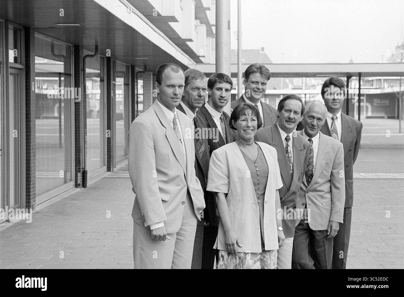 Gruppenfoto, van Vliet, 22-05-1995 Whizgle News, Dutch Desk, Niederlande, 1950-2000 Eine Gruppe von acht Personen steht vor einem modernen Gebäude zusammen und zeigt eine Mischung aus formeller Kleidung. Die Gruppe besteht aus Männern und einer Frau, die alle lächeln und für die Kamera posieren. Ihre Kleidung bietet einen professionellen oder feierlichen Anlass und hebt die Kameradschaft und einen gemeinsamen Moment hervor. Stockfoto