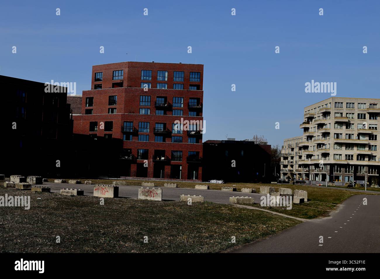 Backsteingebäude und Terrassengebäude prägen das Zuidoever-Viertel im Amsterdamer Zuidas, mit Blick auf einen grünen Park unter klarem Himmel, der das städtische Leben veranschaulicht. Stockfoto