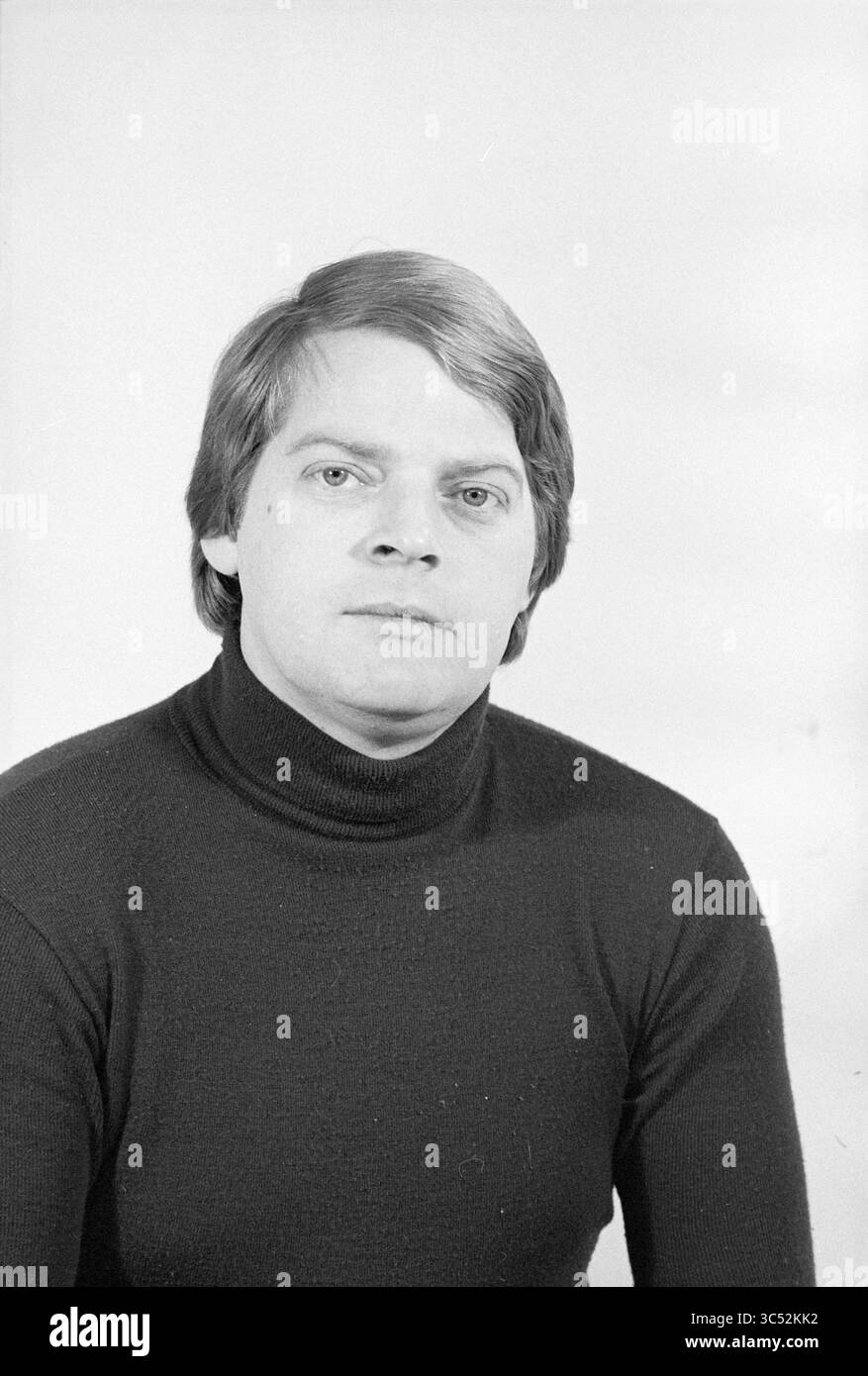 Portrait man Whizgle News, Dutch Desk, Niederlande, 1950-2000 Ein ernsthaft aussehender Mann mit mittellangen Haaren mit schwarzem Rollkragenkragen, der den Betrachter mit einem neutralen Ausdruck direkt anblickt. Stockfoto