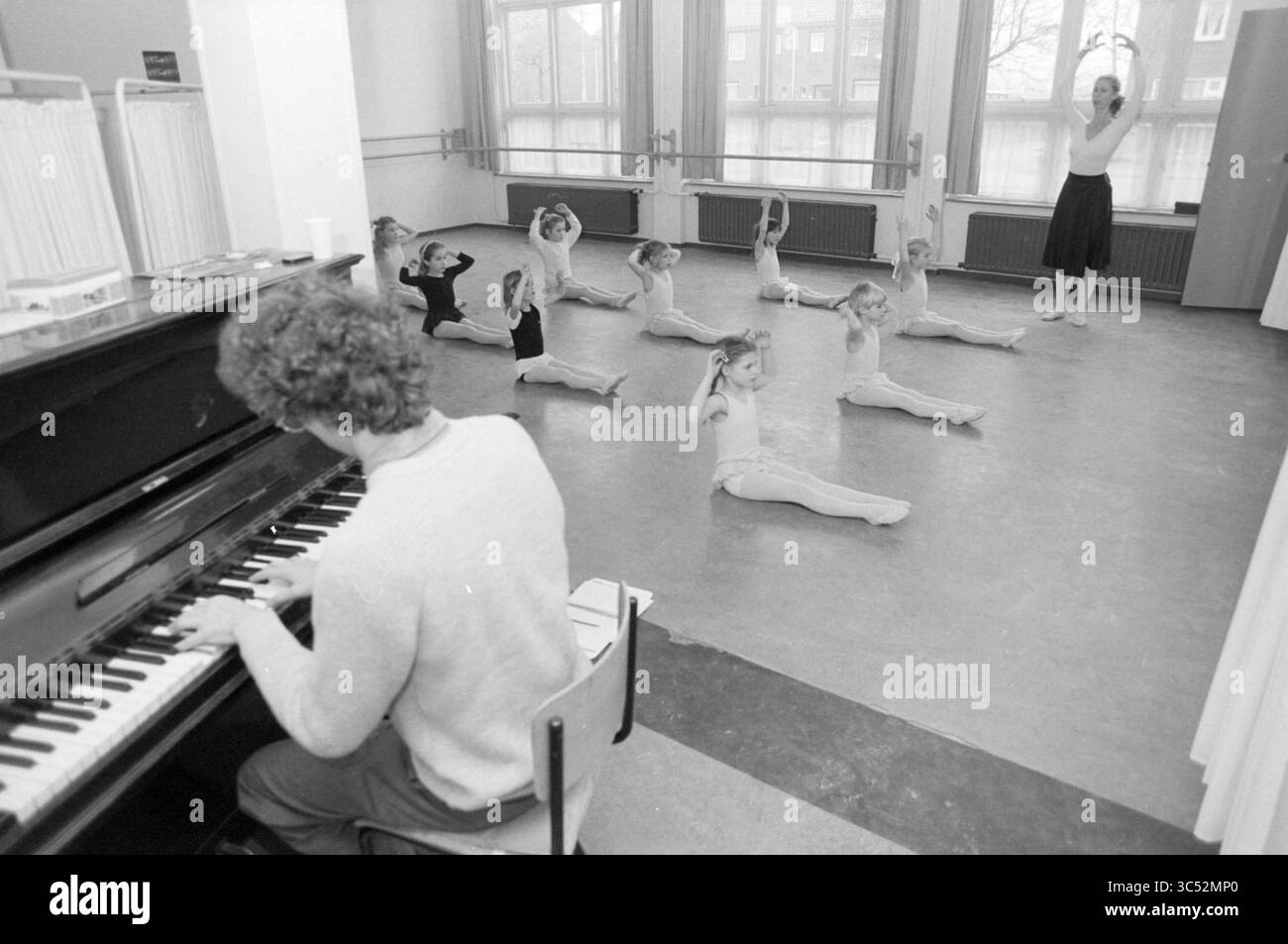 Kinderballettunterricht, 04-02-1987 Whizgle News, Dutch Desk, Niederlande, 1950-2000 Ballettunterricht, bei dem junge Tänzer ihre Bewegungen unter der Leitung eines Ausbilders üben. Ein Pianist spielt im Vordergrund und verleiht der Atmosphäre der Kreativität und Konzentration Musik. Stockfoto