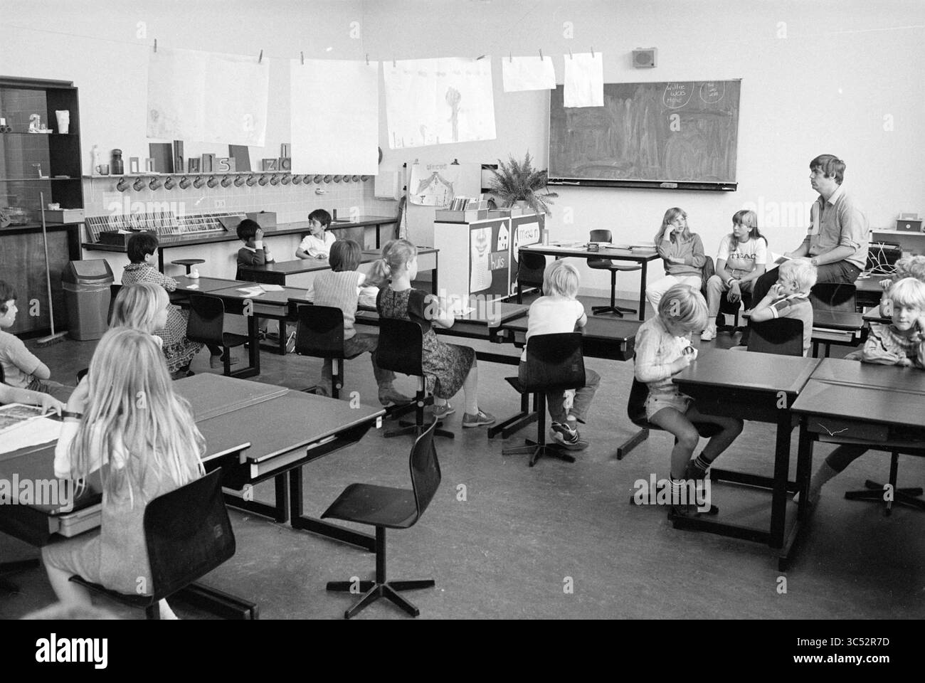 Innere der Schule de Peppelaar (Rathaus), Schulen, 10-09-1981 Whizgle News, Dutch Desk, Niederlande, 1950-2000 Eine Klassenszene, in der Kinder verschiedene Aktivitäten ausüben, wobei einige an Schreibtischen sitzen, andere einem Lehrer zuhören und an den Wänden Kunstwerke ausgestellt werden. Das Layout spiegelt eine typische Schulumgebung wider und fördert das Lernen und die Kreativität. Stockfoto