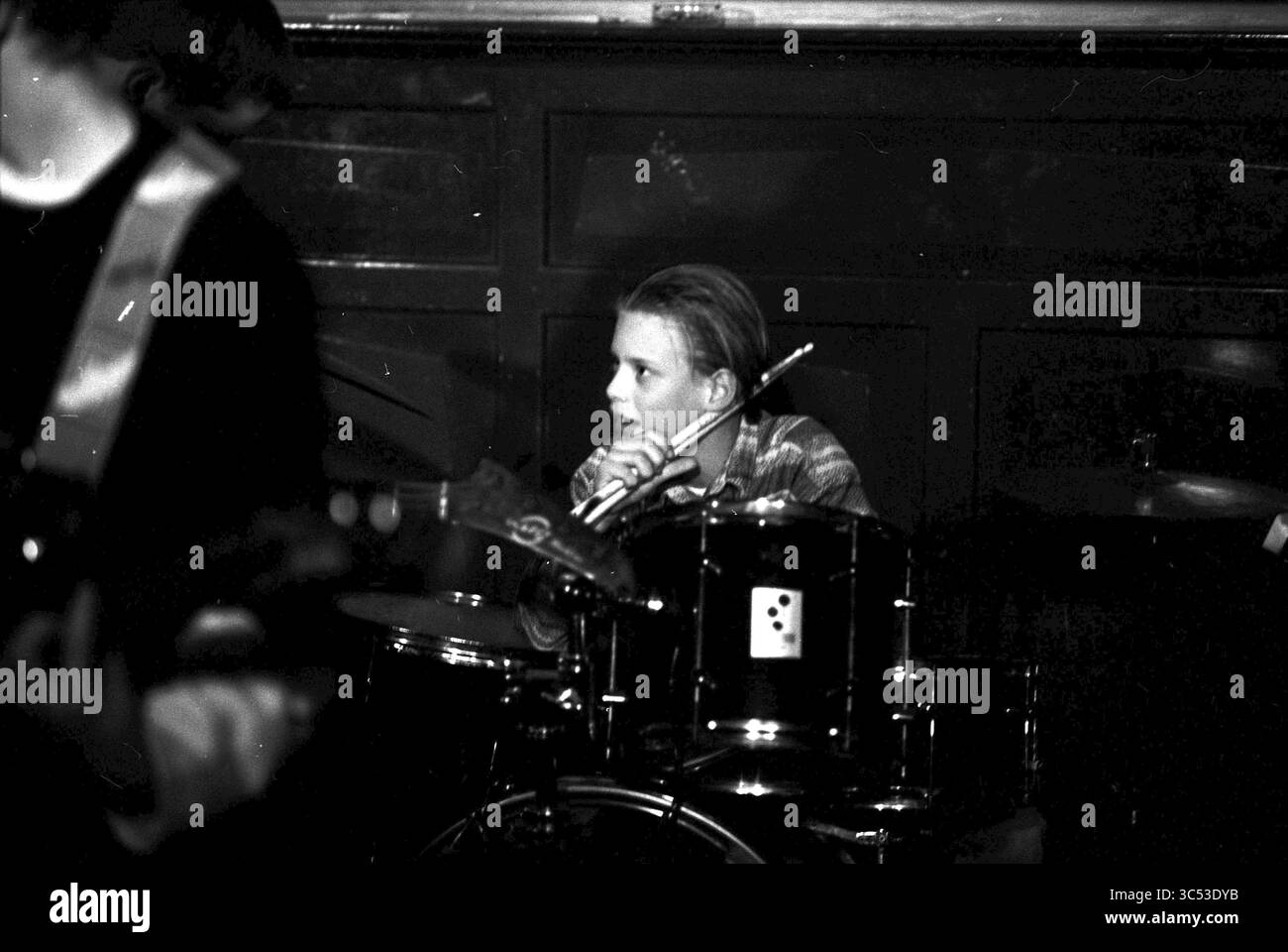 Junge Band, Taverna Imperial, H'lem, Haarlem, Niederlande, 28-02-1996 Whizgle News, Dutch Desk, Niederlande, 1950-2000 Ein junger Schlagzeuger konzentrierte sich intensiv auf seinen Auftritt, umgeben von Bandmitgliedern in einem lebhaften Setting. Seine Konzentration hebt die Energie der Musik hervor, während die kontrastierenden Schatten der Szene Tiefe verleihen. Stockfoto