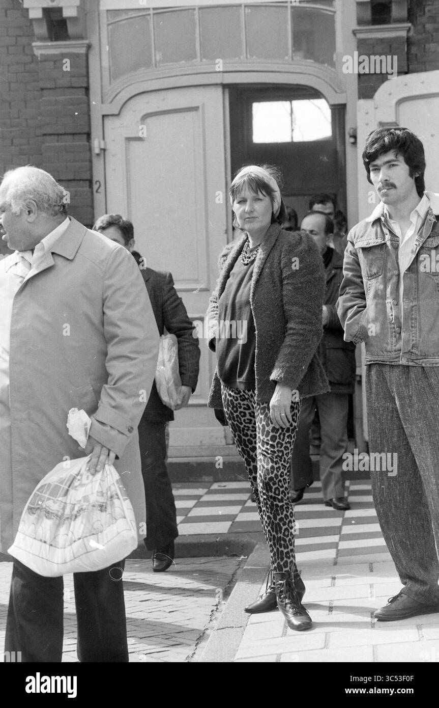 Eine Frau und einige Männer vor einer türkischen Moschee Whizgle News, Dutch Desk, Niederlande, 1950-2000 Eine Gruppe von Einzelpersonen ist vor einem Gebäude versammelt, wobei zwei Personen im Vordergrund stehen. Eine Person in stylischen Hosen mit Tiermotiv strahlt Selbstvertrauen aus, während eine andere in einer Jeansjacke in der Nähe steht, beides inmitten einer hektischen Menschenmenge. Die Atmosphäre lässt eine lebhafte urbane Szene vermuten. Stockfoto
