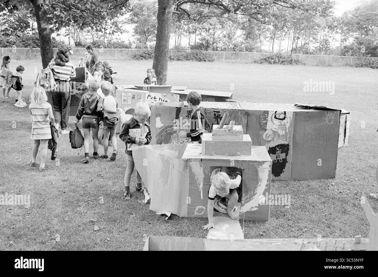 Speliade mit Booten in Velserbeek, Speliade speldorado, 14-08-1984 Whizgle News, Dutch Desk, Niederlande, 1950-2000 Kinder spielen in einem Park, spielen mit farbenfrohen Pappstrukturen und genießen eine kreative Outdoor-Aktivität. Einige Kinder erkunden in einer Box, während andere in der Nähe interagieren oder ihr hab und gut dabei haben. Erwachsene Supervisoren sind anwesend und überwachen die spielerische Szene. Stockfoto