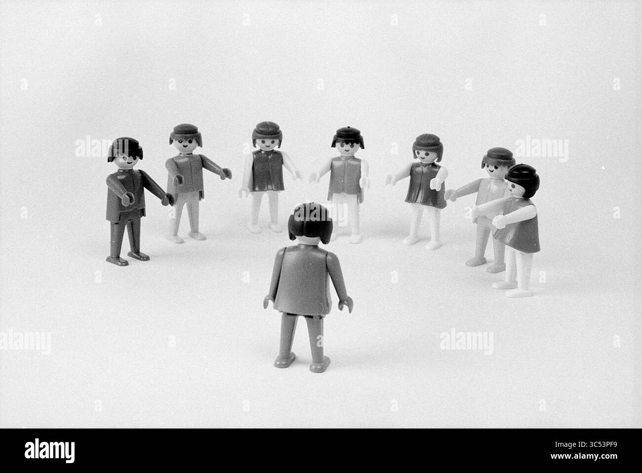 Hustles with Stories Rijnland I - II - III, Verschiedenes, 22-05-1978 Whizgle News, Dutch Desk, Niederlande, 1950-2000 Eine Gruppe von Playmobil-Figuren steht im Kreis, wobei eine Figur in der Mitte den anderen zugewandt ist. Die umliegenden Figuren wirken engagiert und schaffen eine Szene der Interaktion und des Fokus. Stockfoto