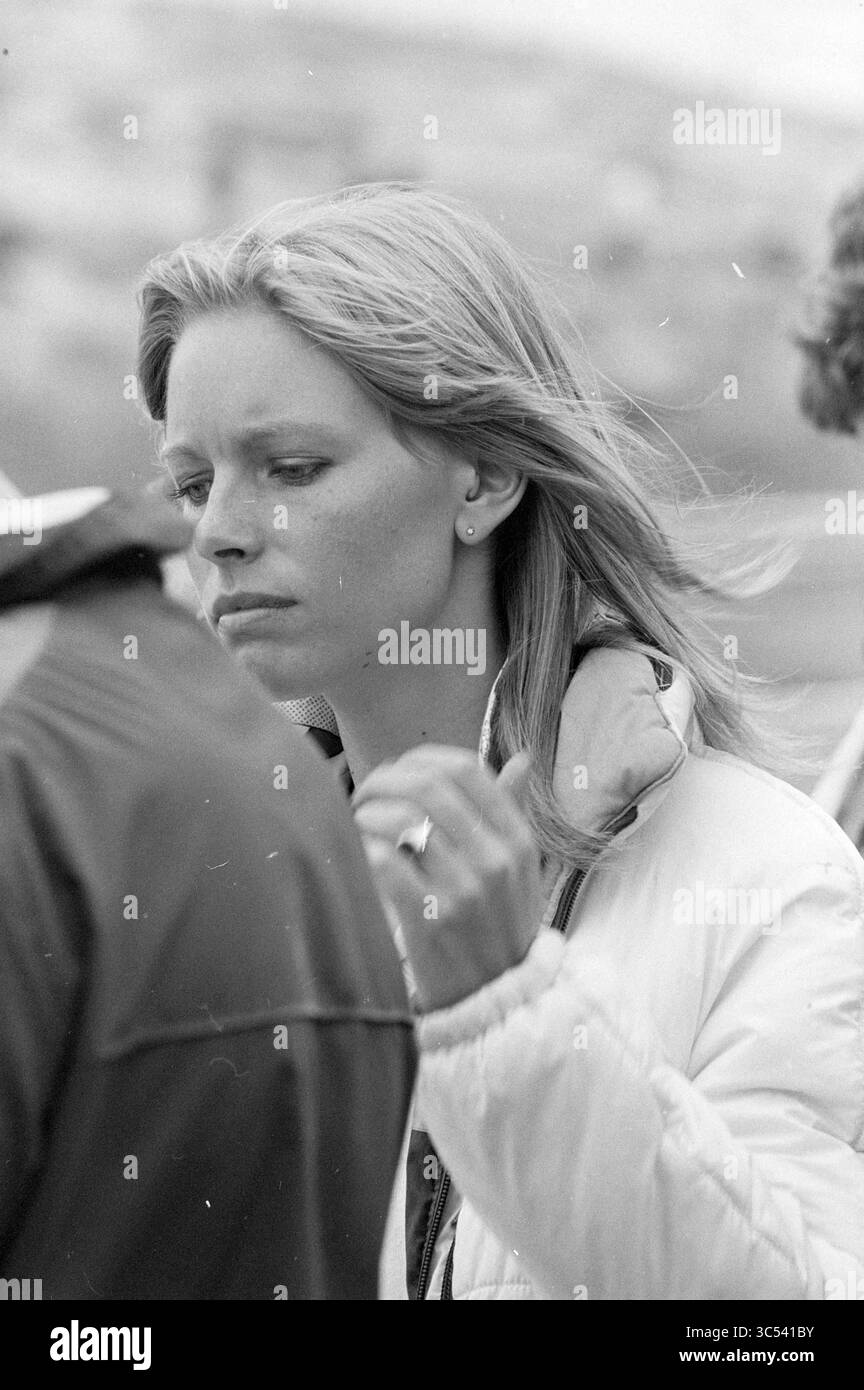 Guest Corner Grand Prix, Grand prix, 29-08-1980 Whizgle News, Dutch Desk, Niederlande, 1950-2000 Eine Frau mit langen, fließenden Haaren taucht tief in Gedanken auf, gekleidet in eine leichte Jacke. Ihr Ausdruck ist kontemplativ, da sie mit den Menschen um sie herum interagiert und einen Moment der Reflexion in einer geschäftigen Umgebung andeutet. Stockfoto