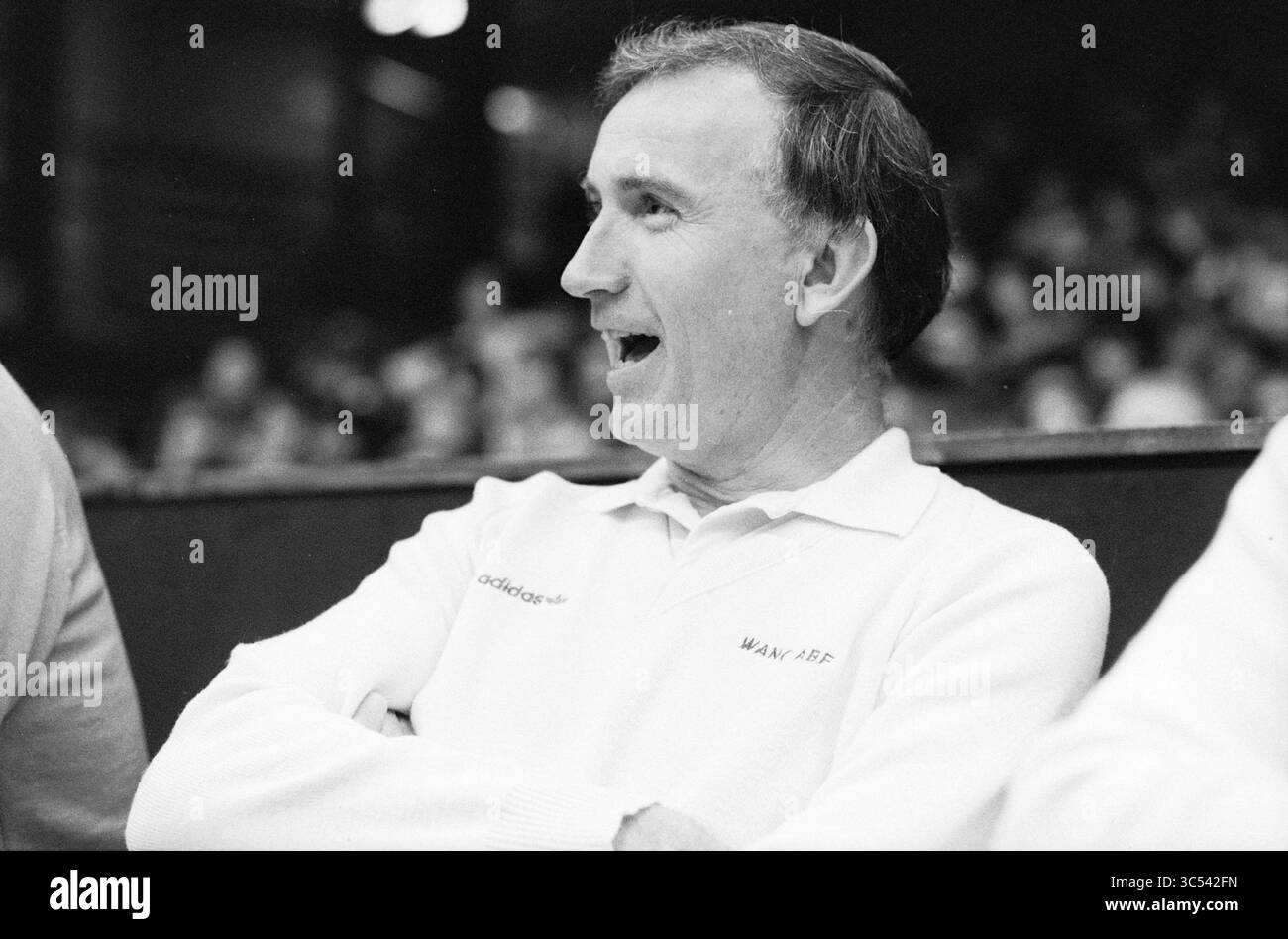 Basketballfinale den Bosch gegen den Helder oder BSW-Porträt von A (früher?) Spieler Whizgle News, Dutch Desk, Niederlande, 1950-2000 Ein Mann mit einem fröhlichen Ausdruck führt Gespräche, der ein helles Poloshirt mit Logo trägt. Seine Frisur und sein Verhalten lassen vermuten, dass er sich in einer lebhaften Umgebung wohl fühlt. Stockfoto