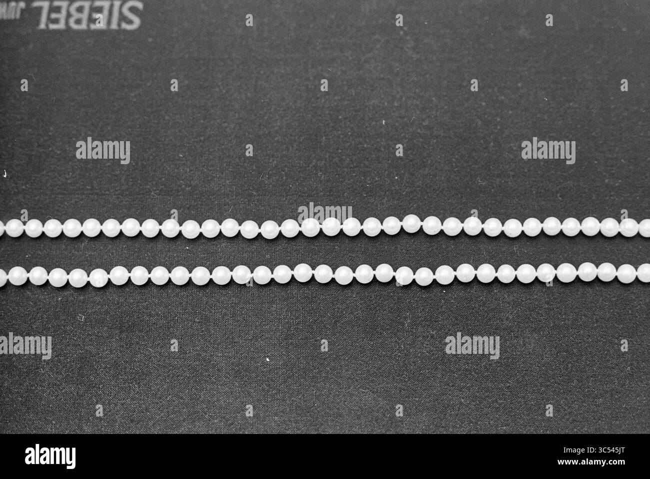Pearls at Siebel Jewelers, 00-00-1972 Whizgle News, Dutch Desk, Niederlande, 1950-2000 zwei elegante, durchscheinende Perlen liegen parallel zueinander vor dunklem Hintergrund. Stockfoto