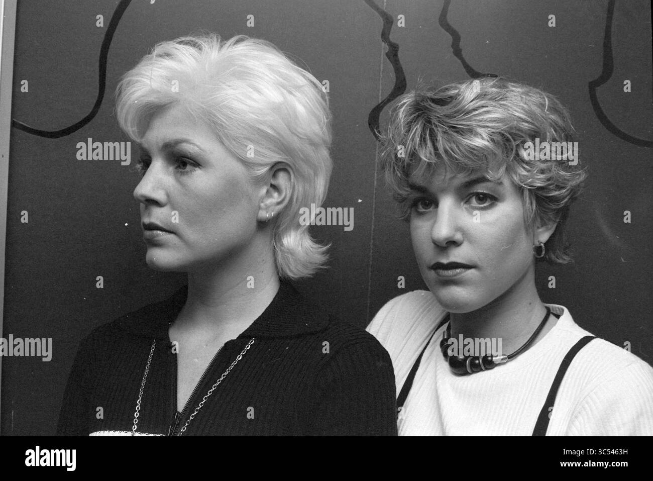 Two Haircuts, Loni Korver, 02-03-1995 Whizgle News, Dutch Desk, Niederlande, 1950-2000 zwei Frauen posieren Seite an Seite, jede von ihnen präsentiert ihre einzigartigen Frisuren und Modeschöpfe. Die linke hat schlanke, gestylte blonde Haare, während die rechte einen zerzausten, lässigen Look hat. Ihre Ausdrucksformen vermitteln eine Mischung aus Selbstvertrauen und Ausgewogenheit, vor einem Hintergrund subtiler Profile. Stockfoto
