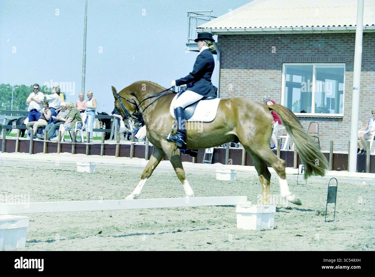 Niederländische Dressurmeisterschaft, Hoofddorp, Niederlande, 28-05-2003 Whizgle News, Dutch Desk, Niederlande, 1950-2000 Ein Reiter in formeller Kleidung führt ein Kastanienpferd anmutig durch eine Dressurroutine und zeigt Eleganz und Präzision, während ein Publikum im Hintergrund beobachtet. Stockfoto