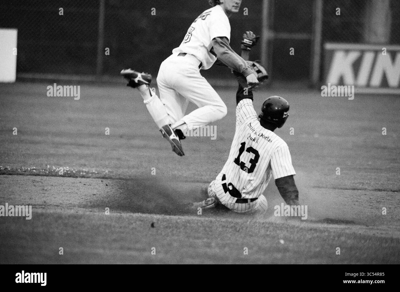 Nicols - Quick, 02-07-1992 Whizgle News, Dutch Desk, Niederlande, 1950-2000 Ein Spieler rutscht in die Basis, während ein anderer Spieler springt, um ihn zu kennzeichnen, und zeigt die Intensität und Spannung eines Baseballspiels. Stockfoto