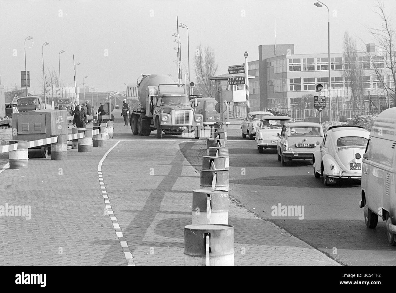 Geschäftige Aktivitäten Prinsenbrug, beschäftigt, 09-04-1968 Whizgle News, Dutch Desk, Niederlande, 1950-2000 Eine geschäftige Straßenszene mit einer Mischung aus Fahrzeugen, darunter ein großer Zementwagen und kleinere Autos, die an Bauschranken vorbeifahren. In der Nähe kann man Menschen bei der Arbeit sehen, während Gebäude und Verkehrszeichen die Stadtlandschaft vervollständigen. Stockfoto