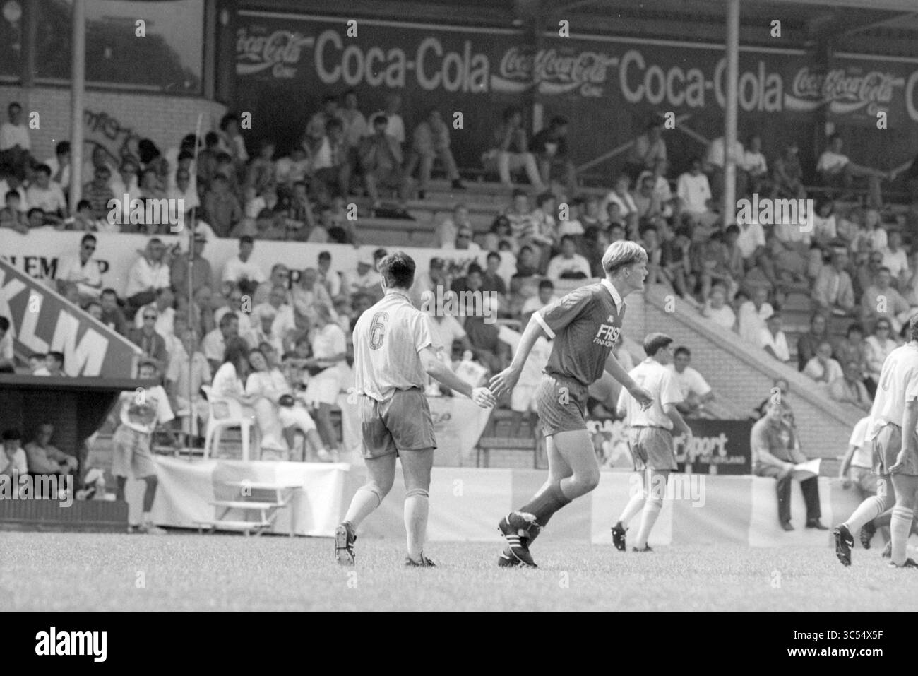 Football Match Haarlem Cup, Haarlem, Niederlande, 00-08-1992 Whizgle News, Dutch Desk, Niederlande, 1950-2000 Ein Fußballspiel in einem überfüllten Stadion, bei dem Spieler in Aktion sind, während Zuschauer von der Tribüne aus zusehen, was die Spannung des Spiels zum Ausdruck bringt. Im Hintergrund sind Werbebanner zu sehen, die die lebhafte Atmosphäre verstärken. Stockfoto