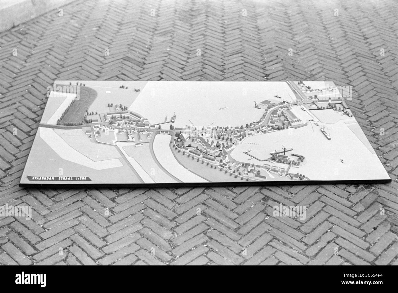 Model Spaarndam Whizgle News, Dutch Desk, Niederlande, 1950-2000 Ein detailliertes Modell, das eine Küstenregion darstellt und verschiedene Strukturen wie Gebäude, Schiffe und Bäume entlang von Wasserstraßen und Landformen zeigt. Stockfoto