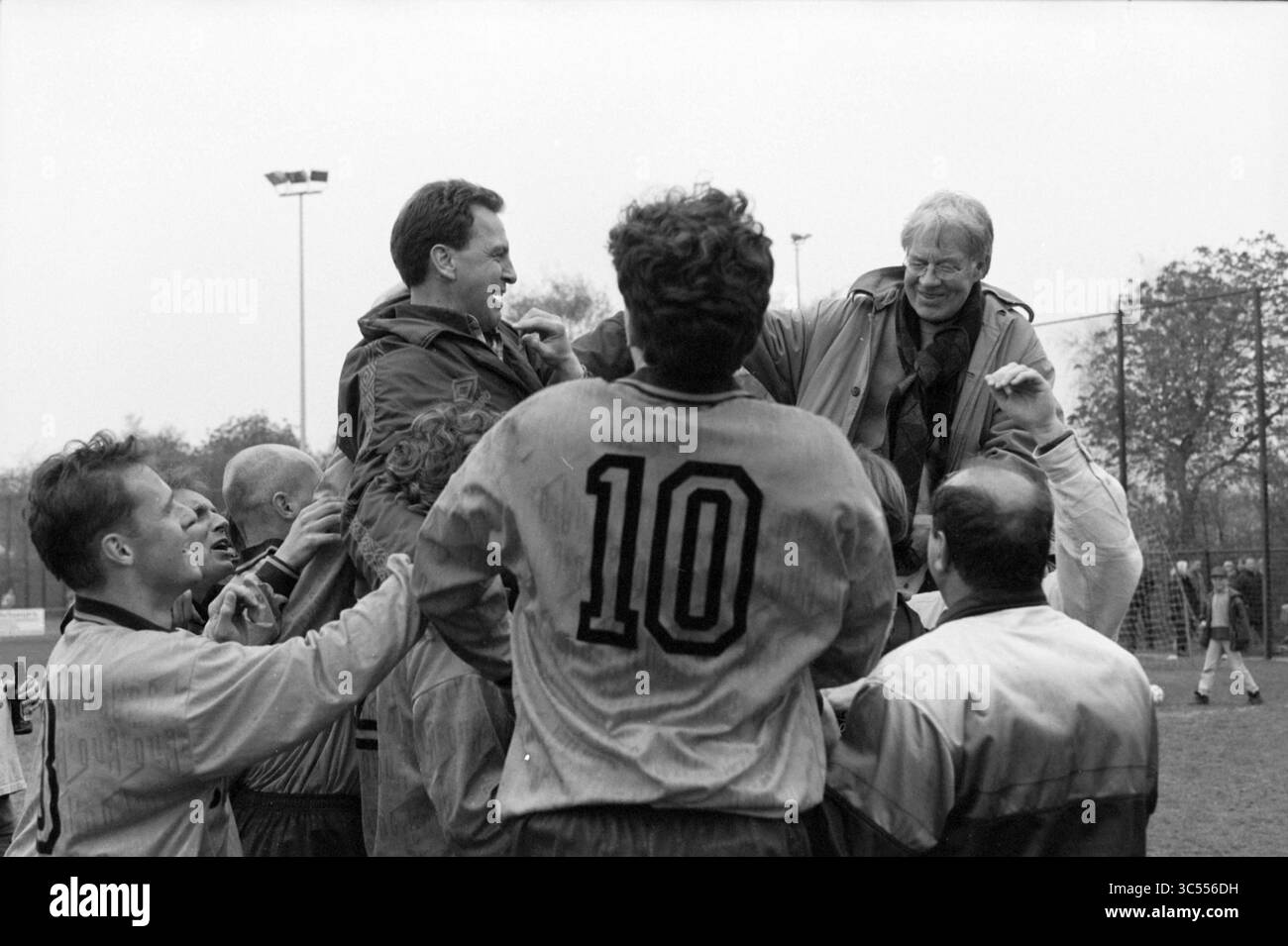 Kennemerland Champion, 25-04-1997 Whizgle News, Dutch Desk, Niederlande, 1950-2000 Eine Gruppe von Fußballspielern feiert einen bedeutenden Sieg, indem sie eine lächelnde Figur in der Luft inmitten einer fröhlichen Menge hebt und die Spannung und Kameradschaft des Augenblicks zeigt. Stockfoto