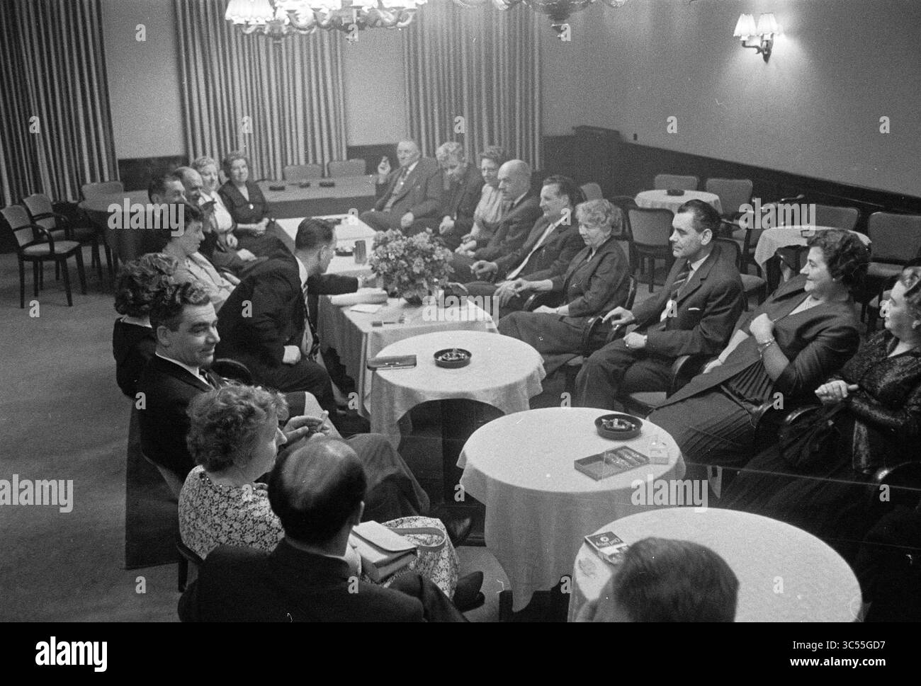 Spezialkonvertierung N.B.M., Haarlem, N.V.V., 16-02-1961 Whizgle News, Dutch Desk, Niederlande, 1950-2000 Eine Gruppe von Einzelpersonen nahm an einem formellen Treffen Teil, diskutierte und teilte Ideen. Das Ambiente bietet einfache Tische mit Blumenarrangements, während die Teilnehmer in einer Mischung aus formeller und legerer Kleidung unterschiedliche Ausdrucksformen von Fokus und Vergnügen zeigen. Das Ambiente lässt eine Atmosphäre der Kameradschaft und des Gesprächs unter den Teilnehmern vermuten. Stockfoto