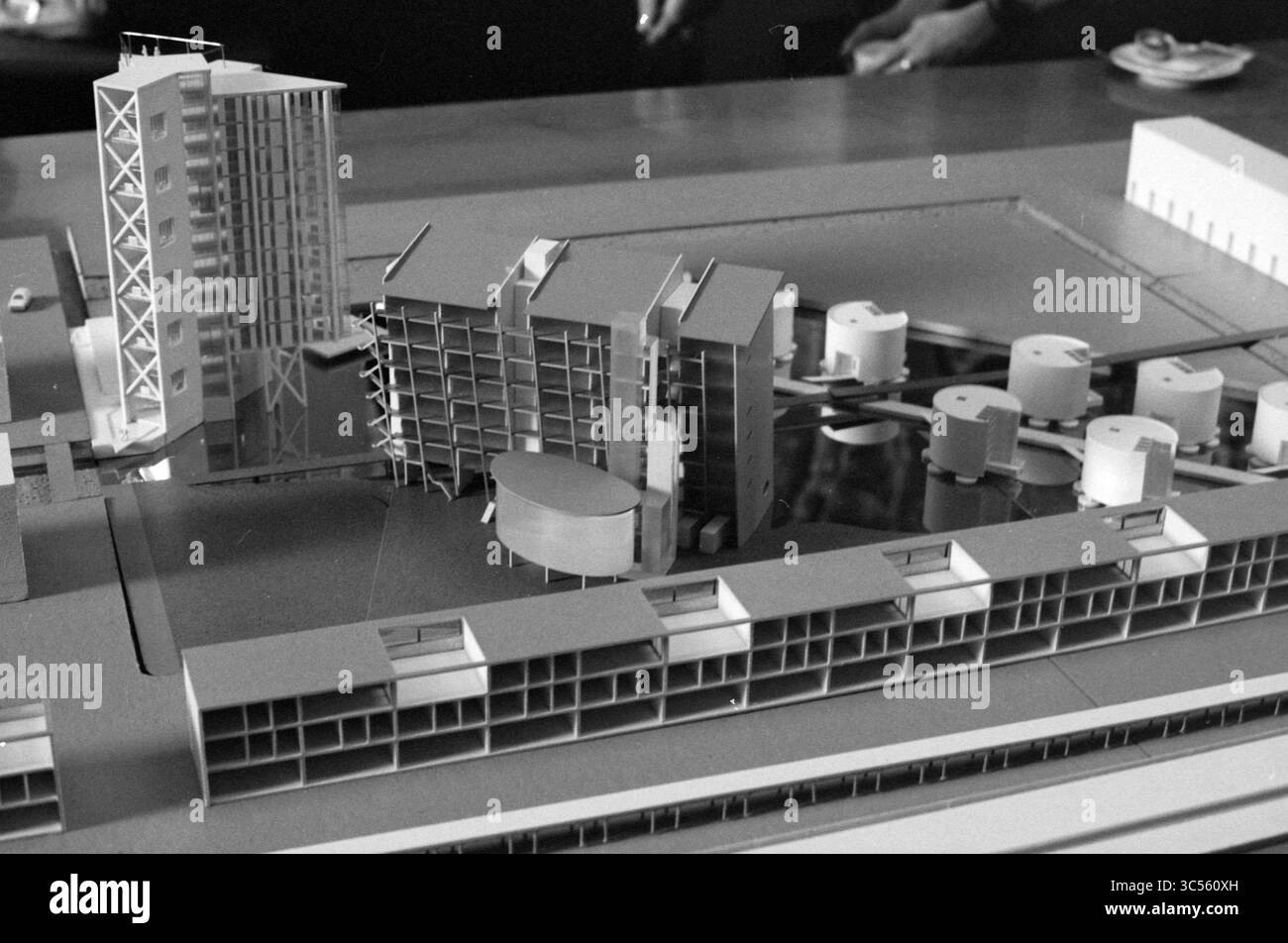 Zusammenkunft der Zuiderpolder-Gebäude, Rathaus, mit Modell, Treffen, 14-01-1987 Whizgle News, Dutch Desk, Niederlande, 1950-2000 Ein Modell eines modernen architektonischen Komplexes mit mehreren Gebäuden, darunter ein Hochhaus und mehrere Unterhäuser, die um ein zentrales Wasserelement angeordnet sind. Zu den herausragenden Designelementen gehören geschwungene und eckige Formen sowie kreisförmige Strukturen, die einen zeitgenössischen Ansatz der Stadtplanung darstellen. Stockfoto