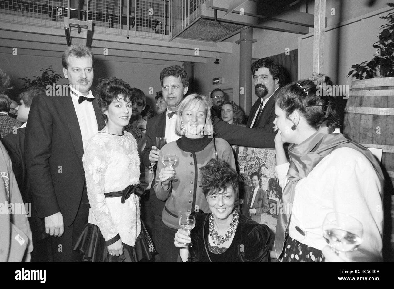 Jubiläum Whizgle News, Dutch Desk, Niederlande, 1950-2000 Ein lebhaftes Treffen von elegant gekleideten Männern und Frauen, die eine feierliche Veranstaltung mit Lächeln, Lachen und Getränken in der Hand genießen. Die Atmosphäre ist festlich und fängt einen Moment der Kameradschaft und der stilvollen Kleidung aus einer früheren Zeit ein. Stockfoto