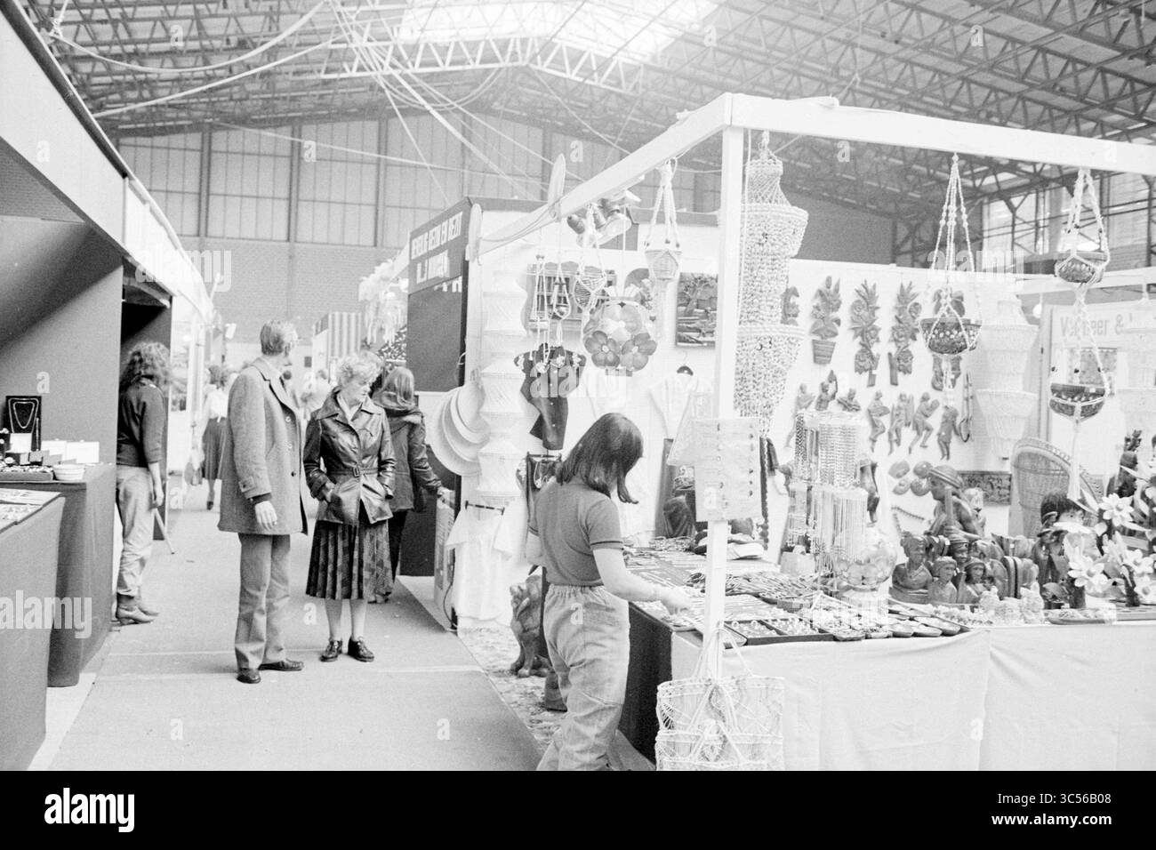 Eröffnung der Frühlingsmesse, Frühlingsmesse, 20-03-1981 Whizgle News, Dutch Desk, Niederlande, 1950-2000 Ein geschäftiger Marktplatz bietet verschiedene Verkaufsstände, an denen handgefertigte Waren, Schmuck und lokale Kunst ausgestellt werden. Besucher entdecken die lebendigen Angebote mit kunstvollen Dekorationen und einzigartigem Kunsthandwerk, das ihre Aufmerksamkeit auf sich zieht. Die Atmosphäre ist voller Neugier und Gemeinschaftsgeist. Stockfoto