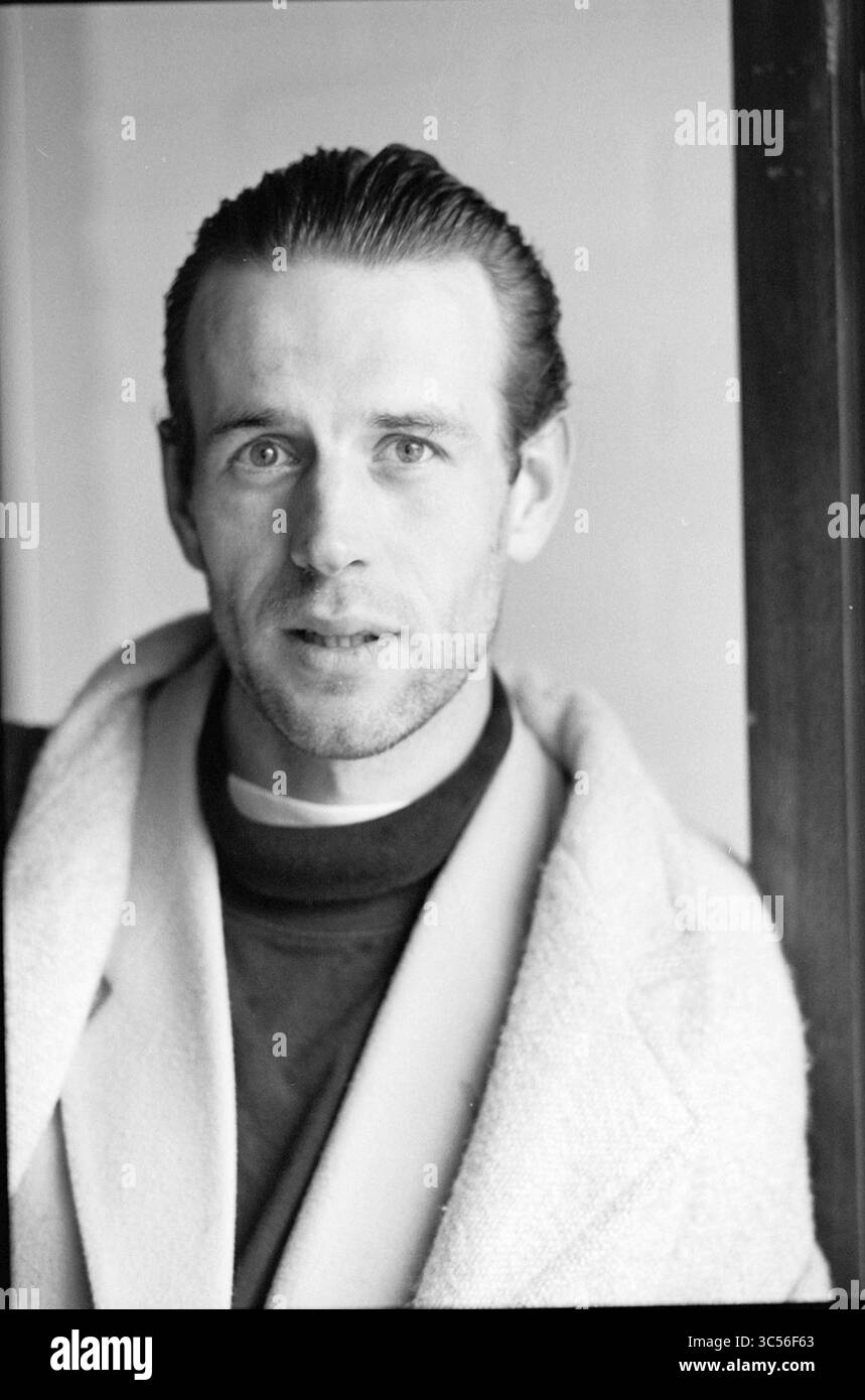 Mann des Spiels, Zandvoort '75, Zandvoort, 16-09-1994 Whizgle News, niederländisches Büro, Niederlande, 1950-2000 Ein Mann mit nachdenklichem Ausdruck steht vor einem schlichten Hintergrund, gekleidet in einem Hemd mit hohem Kragen und einem hellen Mantel. Sein Haar wird zurückgeschliffen, und er blickt direkt auf den Betrachter und strahlt ein Gefühl von Intensität und Ruhe aus. Stockfoto