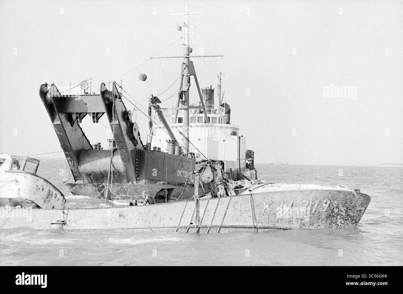 Das Hebe- und Bergungsschiff Octopus hat das Schiff kW 219 Jacomina wieder in Schwung gebracht. Das Schiff sank am 24.07.1965. Polyethylenkugeln wurden verwendet, um den teilweisen Auftrieb des Schiffes wiederherzustellen, damit es angehoben werden konnte., IJmuiden, Niederlande, 2-02-1966 Whizgle News, Dutch Desk, Niederlande, 1950-2000 Ein großes Schiff befindet sich im Wasser und verfügt über markante Maschinen und Ausrüstungen am Bug. Ein weiteres kleineres Boot ist an der Seite befestigt, beide zeigen Anzeichen von Verschleiß. Die Kulisse lässt eine ruhige Meeresumgebung mit minimaler sichtbarer Aktivität vermuten. Stockfoto