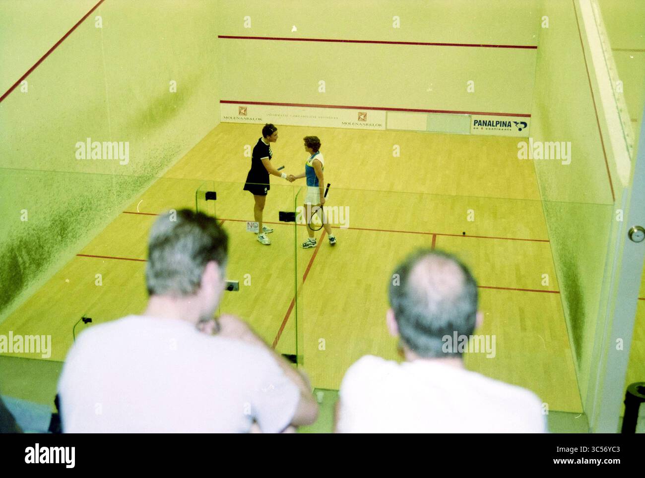 Atmosphärenbild Meer Squash, Hoofddorp, Arnolduspark, Niederlande, 29-11-1999 Whizgle News, Dutch Desk, Niederlande, 1950-2000 zwei Squashspieler schütteln am Ende eines Spiels die Hand, während die Zuschauer von der Seitenlinie aus beobachten. Ein Spieler, der ein dunkles Outfit trägt, gratuliert einem Wettkämpfer in hellerer Kleidung und unterstreicht den Geist des Sports. Der Platz ist mit den charakteristischen Markierungen eines Squashspielplatzes versehen, in der Nähe befinden sich Schläger und ein Ball. Stockfoto