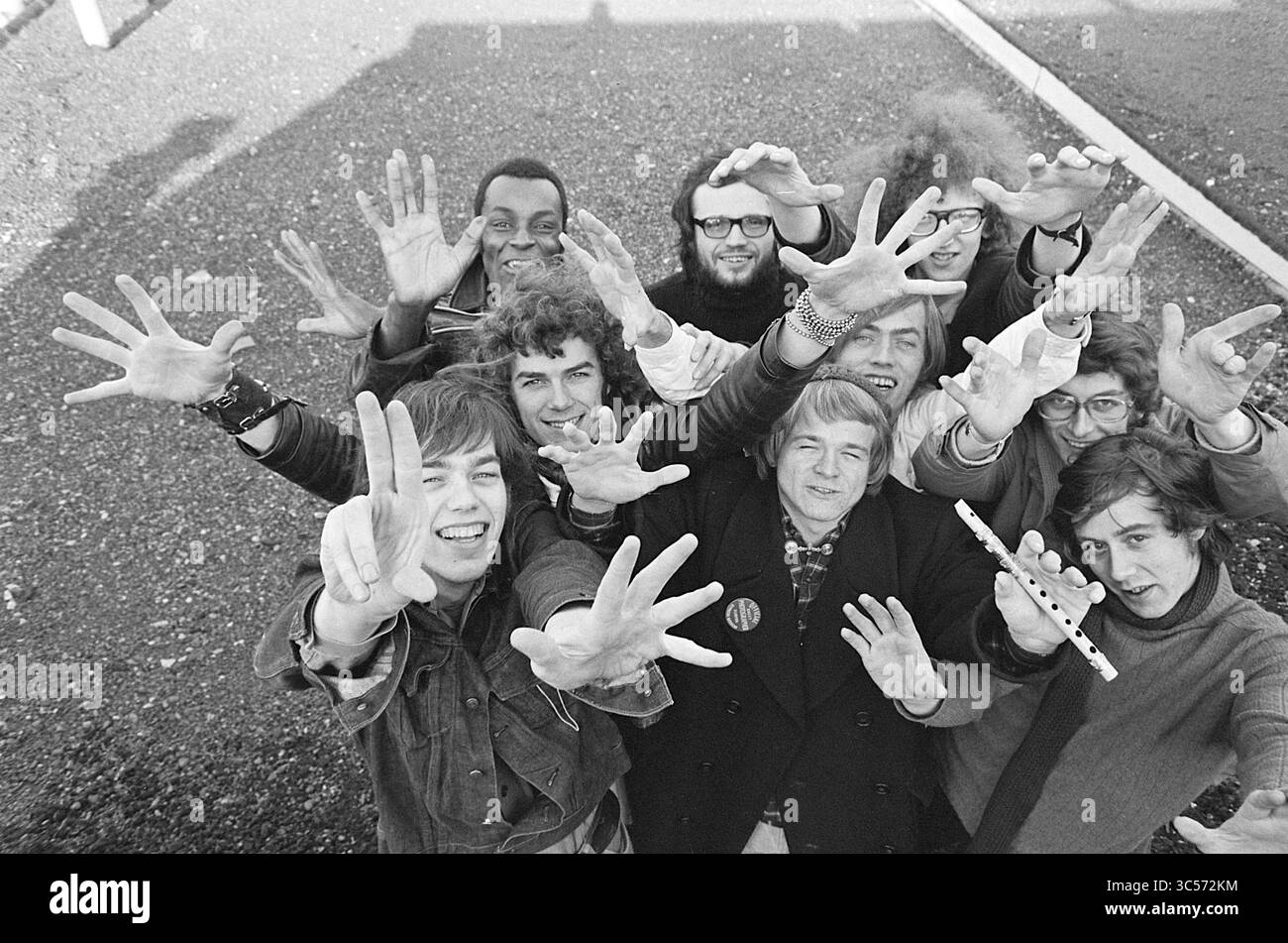 Gruppenfoto von acht jungen Männern Whizgle News, Dutch Desk, Niederlande, 1950-2000 Eine lebendige Gruppe von Einzelpersonen, die lächelnd und lässig posieren, heben ihre Hände enthusiastisch und zeigen ein Gefühl von Kameradschaft und Freude. Jede Person zeigt einen einzigartigen Stil, der den lebendigen Geist ihrer Ära widerspiegelt. Stockfoto