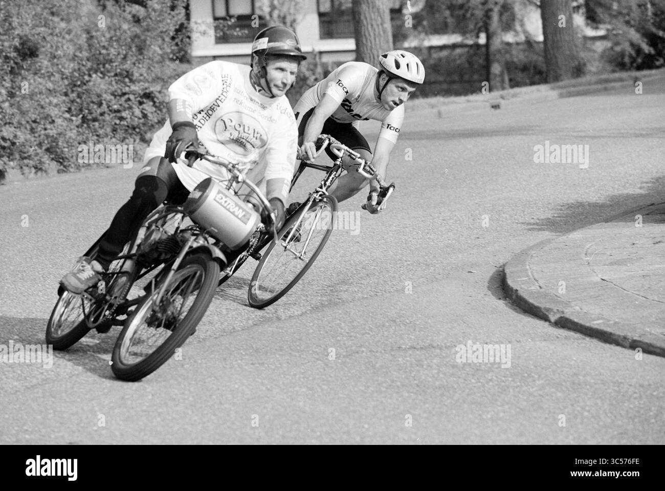 Derny Race, Badh'dorp [Cycling Behind Pacer], Badhoevedorp, 09-06-1997 Whizgle News, Dutch Desk, Niederlande, 1950-2000 zwei Radfahrer legen sich auf einer kurvenreichen Straße in eine scharfe Kurve und zeigen ihren Wettbewerbsgeist. Ein Fahrer ist mit einer einzigartigen Sitzbefestigung ausgestattet, während beide beim Navigieren durch die Kurve fokussierte Ausdrücke anzeigen. Stockfoto