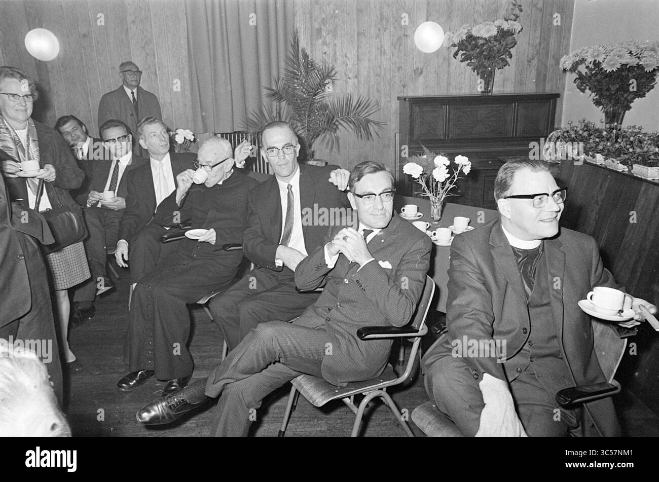 125 Jahre Feier. Kirche, Feste, römisch-katholische Kirchen, römisch-katholische Kirchen, 10-10-1969 Whizgle News, Dutch Desk, Niederlande, 1950-2000 Eine Gruppe gut gekleideter Personen führt Gespräche, während sie in einer formellen Umgebung sitzen und einige Tassen Kaffee halten. Die Atmosphäre vermittelt ein geselliges oder professionelles Treffen mit dekorativen Pflanzen und einer übersichtlichen Kulisse. Stockfoto
