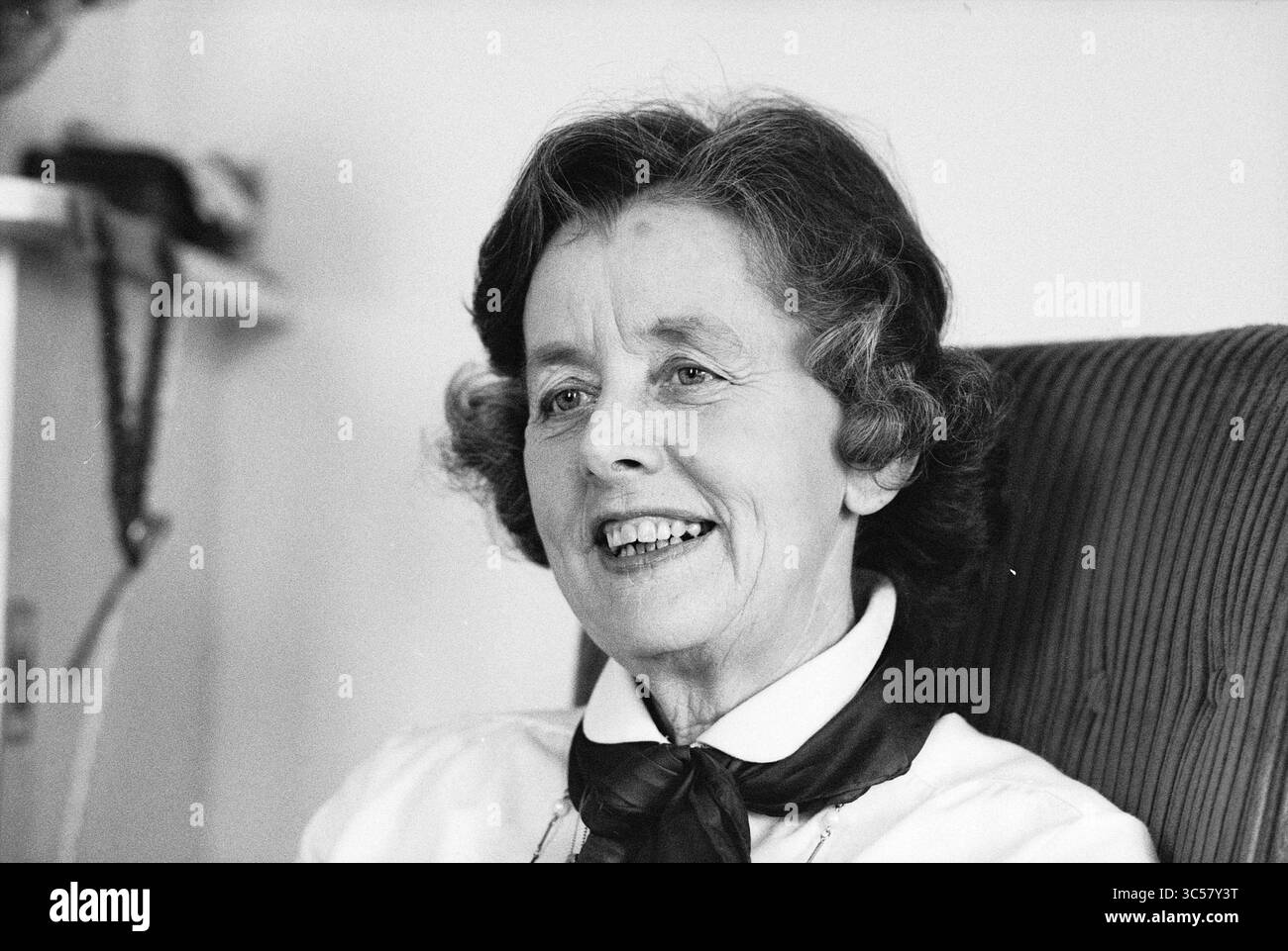 Portrait Ria Hooy VVV Haarlem, Portraits, V.V.V., Haarlem, Niederlande, 05.02.1980 Whizgle News, Dutch Desk, Niederlande, 1950-2000 Eine lächelnde ältere Frau mit weichen Locken und einem stilvollen Schal um den Hals, die Wärme und Weisheit ausstrahlt, während sie sich im Gespräch befindet. Stockfoto