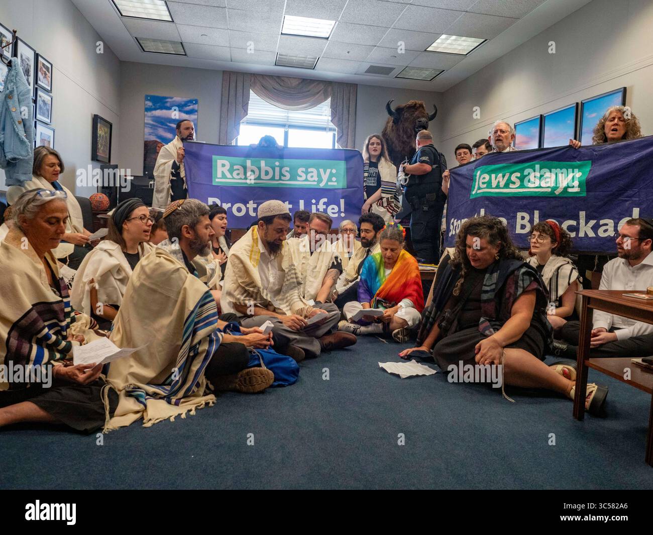 Washington, District of Columbia, USA. Juli 2025. Mehr als zwei Dutzend Rabbiner führen einen Akt des zivilen Ungehorsams im Büro des Mehrheitsführers des US-Senats John Thune durch, um die Aufmerksamkeit auf die Notwendigkeit sofortiger Maßnahmen zur Bereitstellung von Nahrungsmittelhilfe für die Bevölkerung der GazaÃs zu lenken. Ein Mitglied der US Capitol Police bereitet sich auf die Festnahme vor. (Credit Image: © Sue Dorfman/ZUMA Press Wire) NUR REDAKTIONELLE VERWENDUNG! Nicht für kommerzielle ZWECKE! Stockfoto