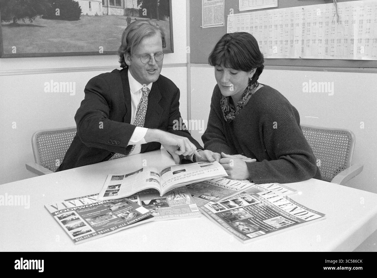 Zweiköpfige Zeitschrift „Vivenda“, VNU, Haarlem, Ceylonpoort, Niederlande, 07-04-1997 Whizgle News, Dutch Desk, Niederlande, 1950-2000 Ein Mann und eine Frau diskutieren an einem Tisch und zeigen auf eine Zeitschrift, während verschiedene Publikationen um sie herum verteilt sind. Sie scheinen zusammenzuarbeiten und Ideen oder Meinungen zu den Inhalten auszutauschen. Stockfoto