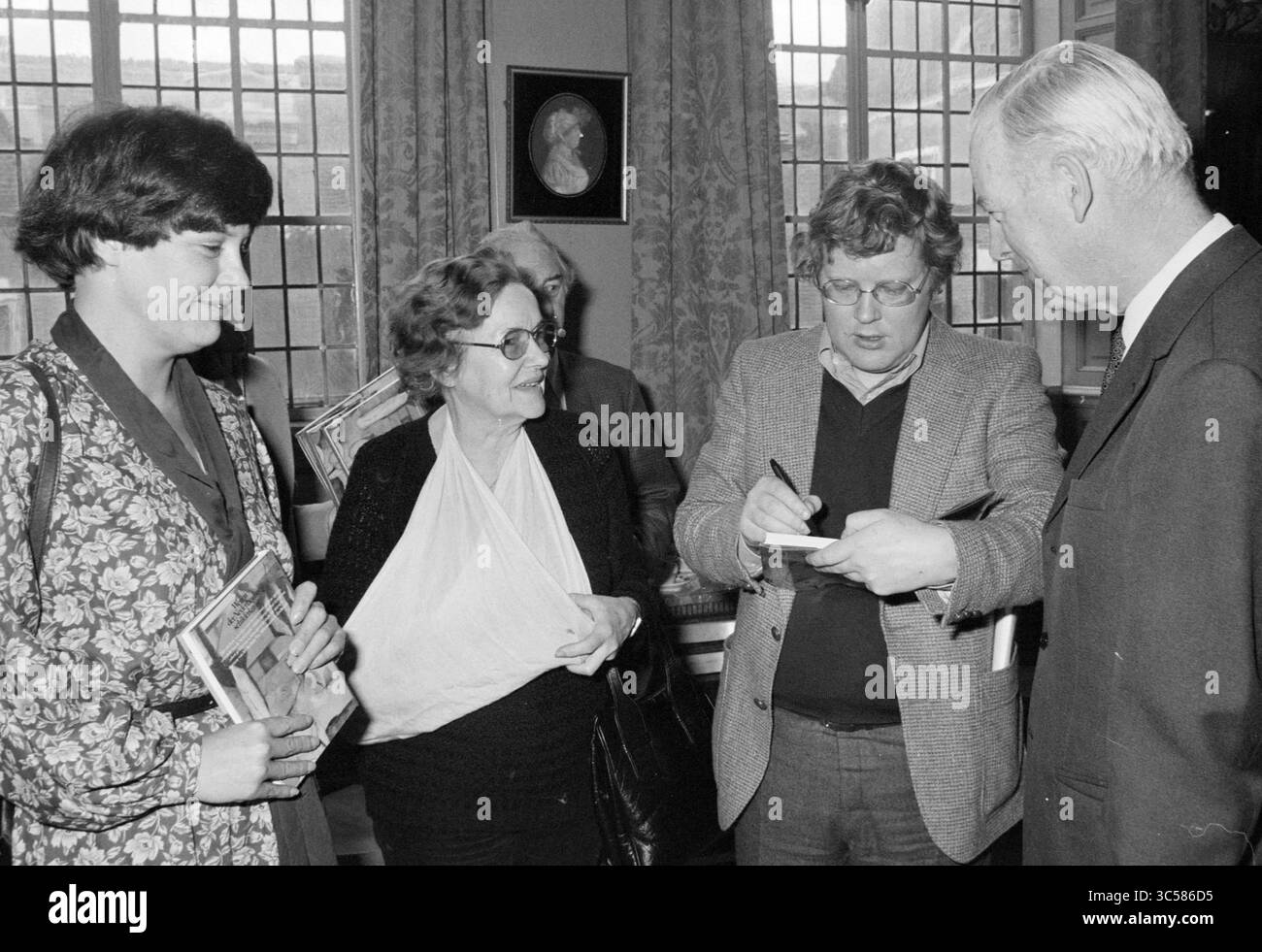 Präsentationsbuch Wege des niederländischen Malers Art Leiden Spectrum, 27-03-1979, Leiden. Mit Rudi Fuchs und Wim T. Schippers Whizgle News, Dutch Desk, Niederlande, 1950-2000 führt Eine Gruppe von vier Personen Gespräche, wobei eine Person Notizen macht, während andere aufmerksam zuhören. Zwei Frauen halten Bücher, während ein älterer Mann den Austausch beobachtet und so eine Atmosphäre der Diskussion und der Intention schafft. Stockfoto