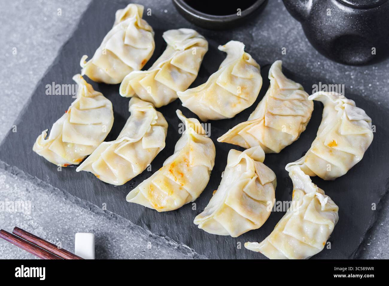 Ein Teller mit frisch gekochten Gyoza-Knödeln. Dies ist eine ideale Vorspeise oder Mahlzeit, die mit Stäbchen gegessen wird. Stockfoto
