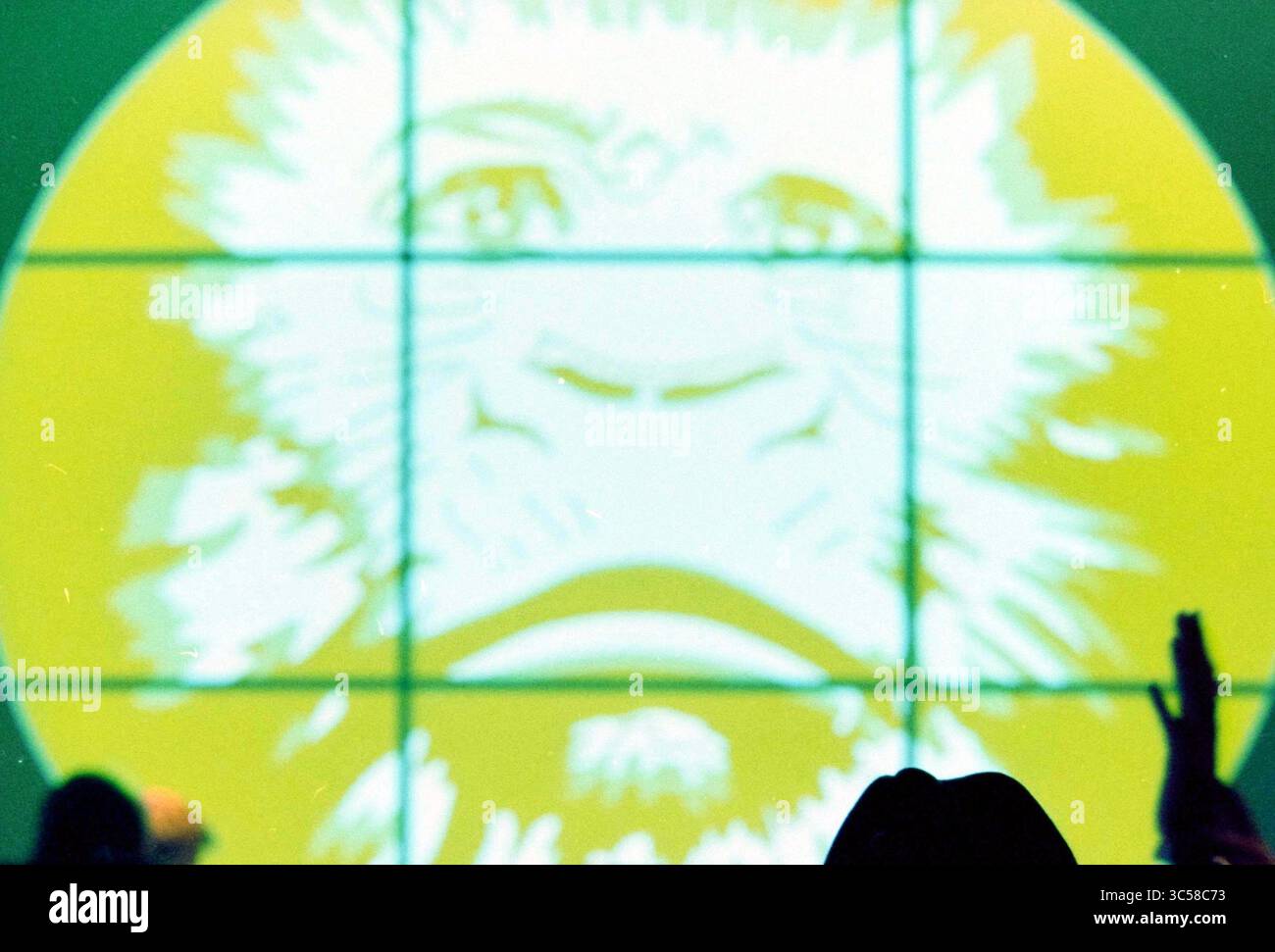 VJ Festival, Nieuwe Vide, Haarlem, Niederlande, 10-01-2003 Whizgle News, Dutch Desk, Niederlande, 1950-2000 vor einem großen kreisrunden Hintergrund wird das Gesicht eines Löwen lebendig dargestellt, während die Silhouetten von Menschen ihre Hände heben und auf einen Moment der Feier oder Verlobung hinweisen. Stockfoto
