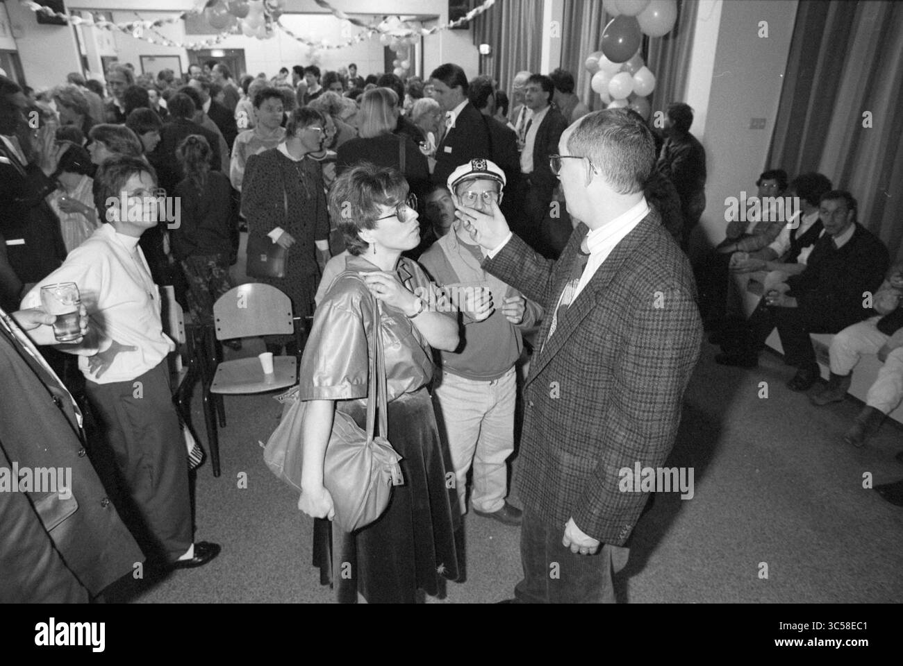Disco Eksjun/festliche Versammlung, 05-11-1989 Whizgle News, Dutch Desk, Niederlande, 1950-2000 Eine lebhafte Versammlungsszene voller Menschen, die eine festliche Atmosphäre genießen, in der sich die Menschen unterhalten, lachen und feiern. Der Raum ist mit Ballons und Bannern dekoriert, was eine fröhliche Kulisse für die Interaktion mit anderen Menschen schafft. Stockfoto