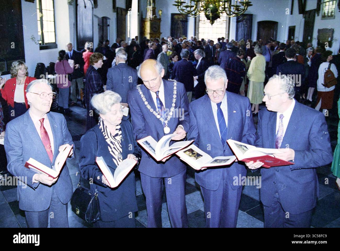 Präsentation des Buches Haarlem 750 Jahre an (ehemalige) Bürgermeister und (ehemalige) Kommissare der Königin im Rathaus, Haarlem, Grote Markt, Niederlande, 30-03-1995. Dutch Desk, Niederlande, 1950-2000 Eine Gruppe von Persönlichkeiten steht zusammen, die sich mit Gesprächen beschäftigen und offene Bücher untersuchen. Sie sind von einer Menschenmenge umgeben, was auf eine formelle Versammlung oder Veranstaltung hindeutet, die wahrscheinlich mit der Geschichte oder lokalen Bedeutung in Zusammenhang steht, angesichts der Anwesenheit der Bürgermeisterkette, die von einer der Einzelpersonen getragen wird. Die Atmosphäre spiegelt ein Gefühl der Gemeinschaft und das gemeinsame Interesse am Material b wider Stockfoto