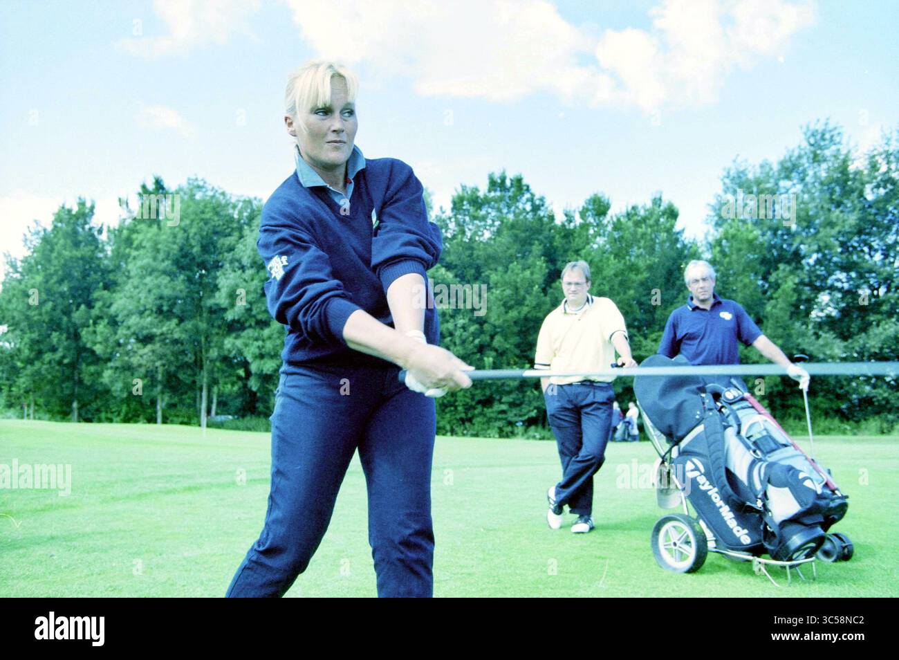 Mitarbeiter des Golfmagazins, auf dem Golfplatz Spaarnwoude, Velsen-Zuid, 09-08-2001 Whizgle News, Dutch Desk, Niederlande, 1950-2000 Ein Golfer schwingt auf dem Platz, konzentriert und entschlossen, während ein paar andere Spieler im Hintergrund beobachten. Das üppige Grün der Landschaft ergänzt die Aktivität und hebt einen Moment der Konzentration im Spiel hervor. Stockfoto