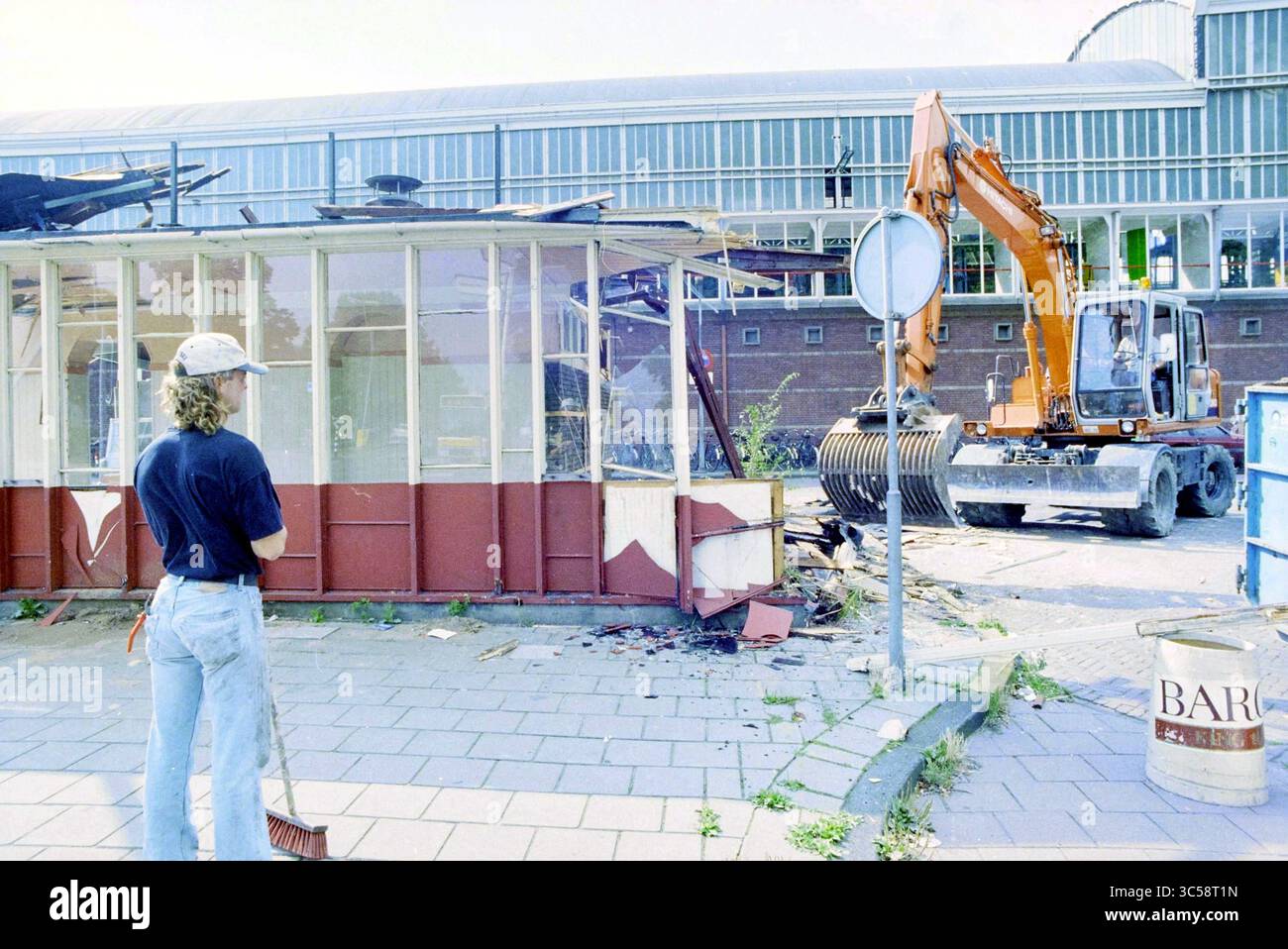 Abbruchkaffeehaus Station, 04-09-1995 Whizgle News, Dutch Desk, Niederlande, 1950-2000 Ein Arbeiter beobachtet, wie ein Bagger ein Gebäude abriss, umgeben von Trümmern und Bauzeichen. Stockfoto