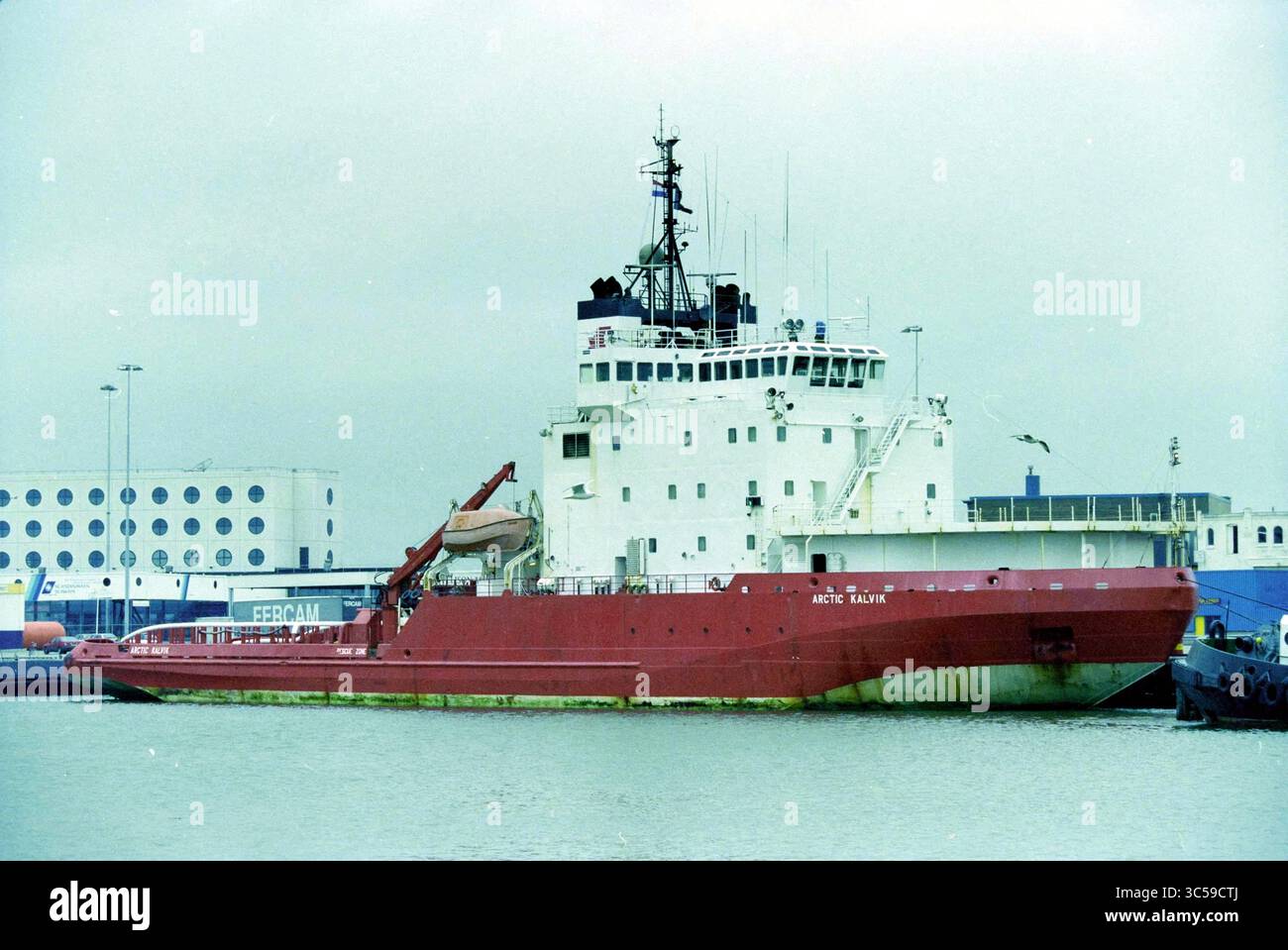 Eisbrecher Arctic Kalvik, IJmuiden, IJmuiden, Niederlande, 26-09-1999 Whizgle News, Dutch Desk, Niederlande, 1950-2000 Ein großes Eisbrecherschiff liegt an einem Hafen an, das einen robusten roten Rumpf und einen markanten Aufbau mit verschiedenen Antennen und Ausrüstungen aufweist. Die Kulisse bietet Industriegebäude und einen ruhigen Hafen, der eine Atmosphäre maritimer Aktivitäten schafft. Stockfoto