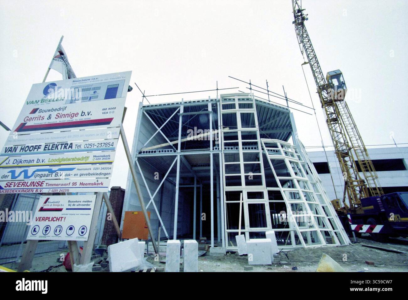 Neubauunternehmen Van Beelen IJmuiden, IJmuiden, Niederlande, 30-11-1998 Whizgle News, Dutch Desk, Niederlande, 1950-2000 Eine Baustelle mit einem teilweise gebauten Gebäude mit einzigartigem architektonischem Design. Es sind verschiedene Stützbalken und Gerüste sowie ein großes Bauschild mit Details zum Projekt und den beteiligten Unternehmen sichtbar. Im Hintergrund steht ein Kran, der auf laufende Arbeiten und Entwicklungen hinweist. Stockfoto