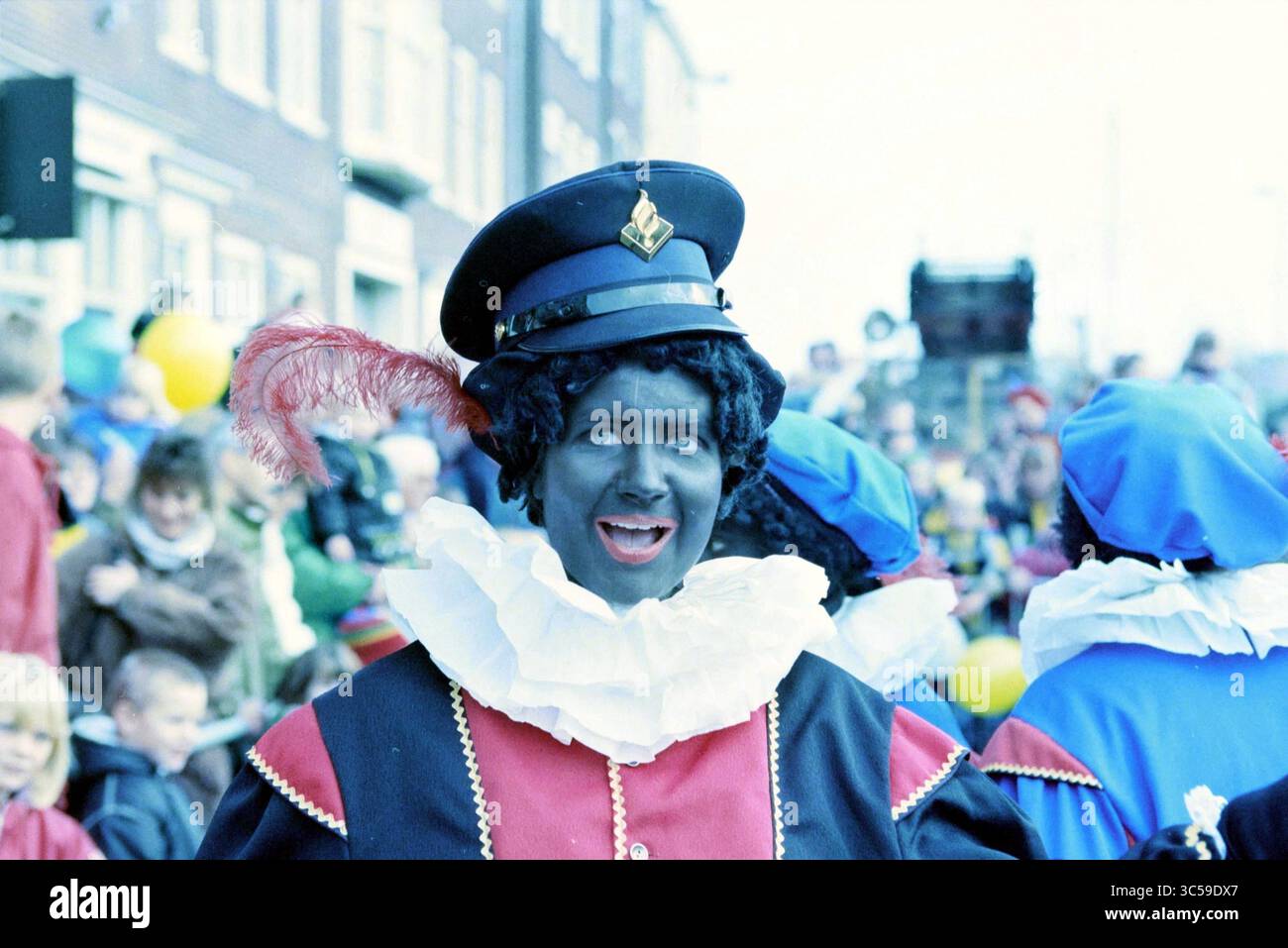 Ankunft von St. Nicholas, Haarlem, Niederlande, 15-11-1996 Whizgle News, Dutch Desk, Niederlande, 1950-2000 Ein Darsteller in einem lebendigen Kostüm mit markantem Federhut und Rüschenkragen nimmt an einer festlichen Parade Teil, umgeben von jubelnden Zuschauern. Die Atmosphäre ist lebhaft, gefüllt mit farbenfrohen Dekorationen und fröhlichen Ausdrücken. Stockfoto