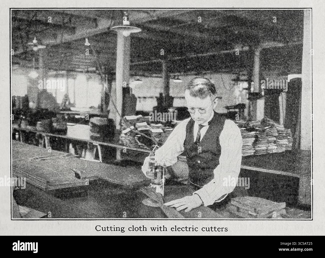 Das Schneiden von Tuch mit elektrischen Schneidern aus dem Buch The Clothes We Wear der Serie The Journey Club Travels by Carpenter, Frank G. (Frank George), 1855-1924 erschienen New York, Cincinnati: American Book Company 1926 in diesem Buch reist der Journey Club, um selbst zu sehen, wie ihre Kleidung hergestellt wird. Stockfoto