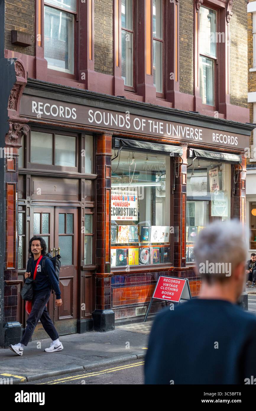 Shopper spazieren vorbei an den legendären Klängen des Universe Plattenladens in Soho, London, einem beliebten Reiseziel für Vinyl, Soul, Funk und elektronische Musik. Stockfoto
