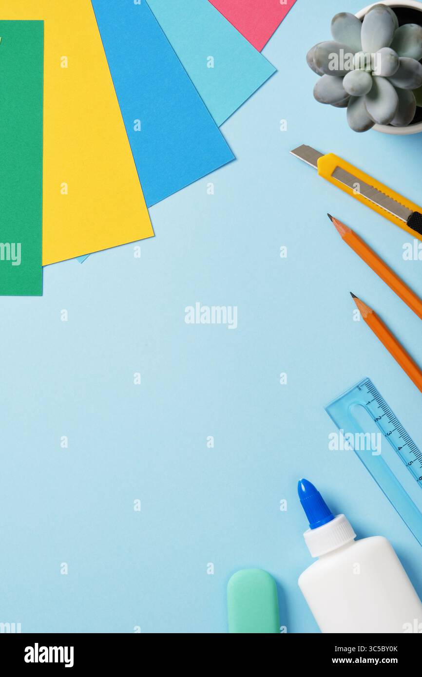 Zubehör für Papierkunst-Hobby: Bastelmesser, Bleistift, Radiergummi, Leim, Lineal, farbiges Papier. Platz für Ihren Text. Papier bastelt Arbeitstisch Flatlay. Stockfoto